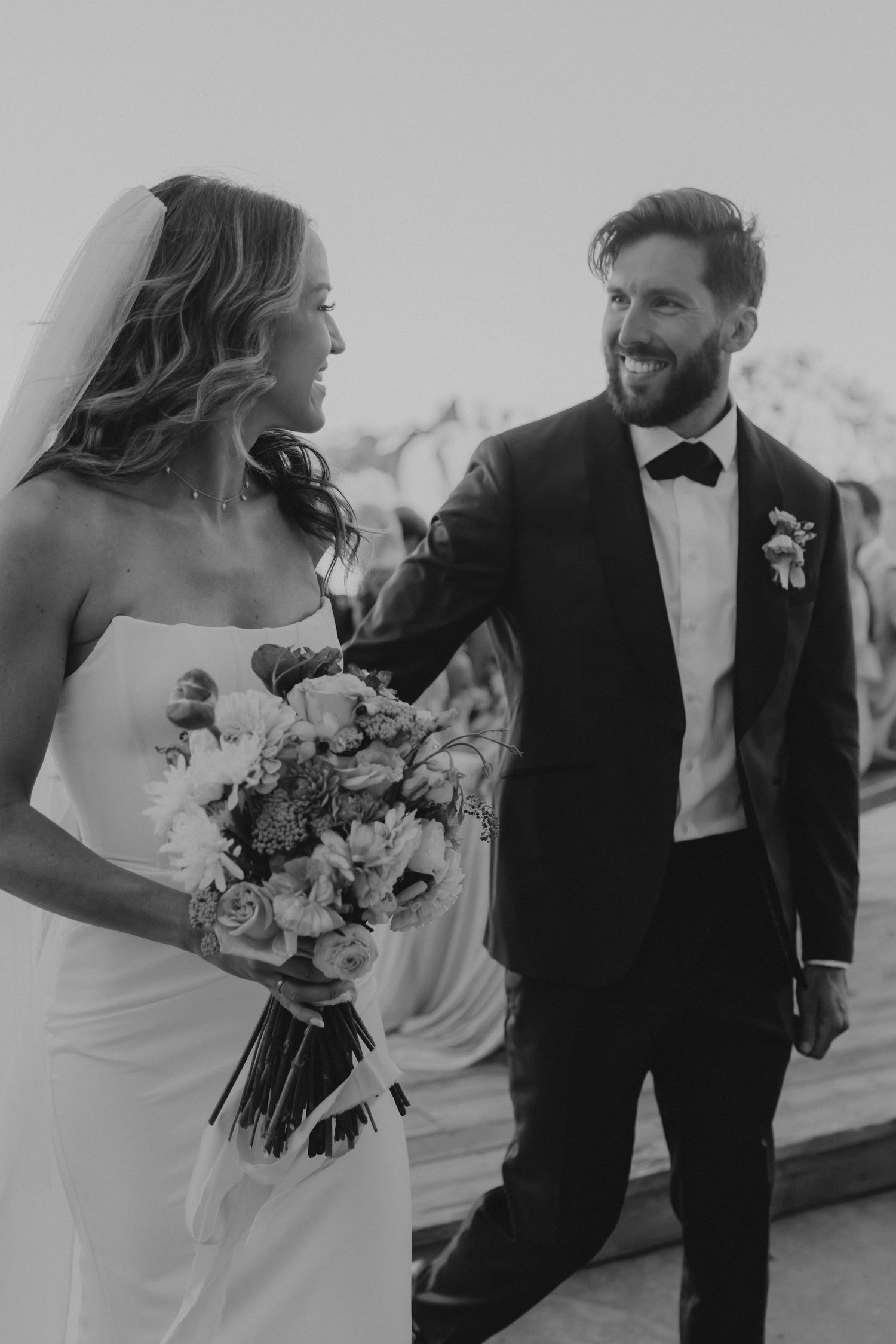 Black and white candid wedding photos showing happy couple sharing intimate moments with bouquet and formal attire.