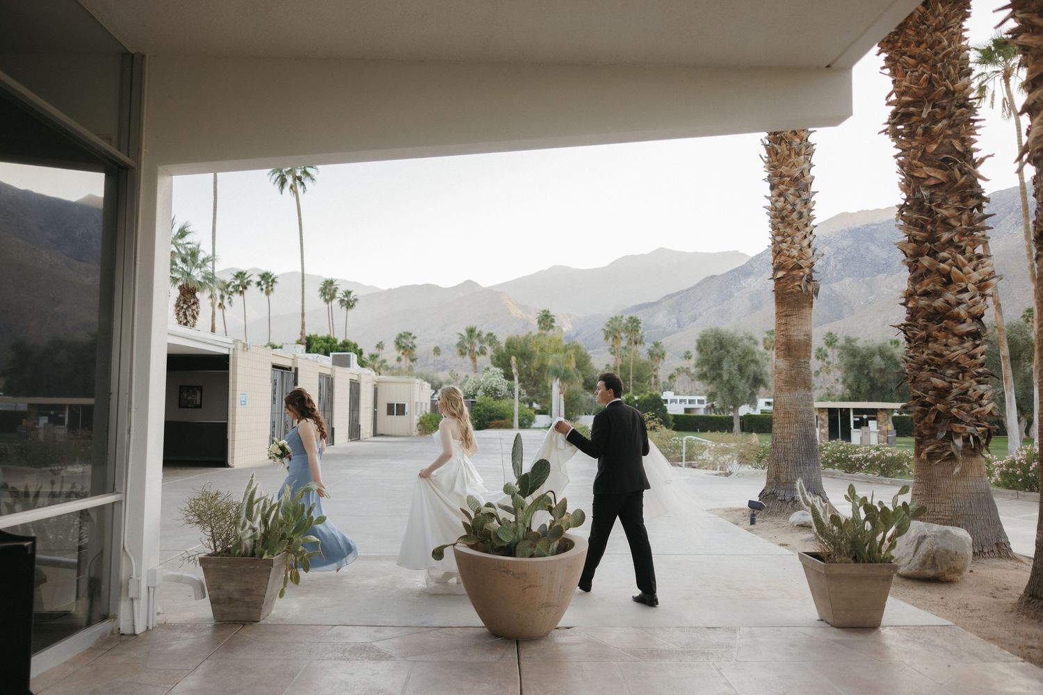 Bride and groom sharing a first look moment on a covered patio with palm trees and mountains.