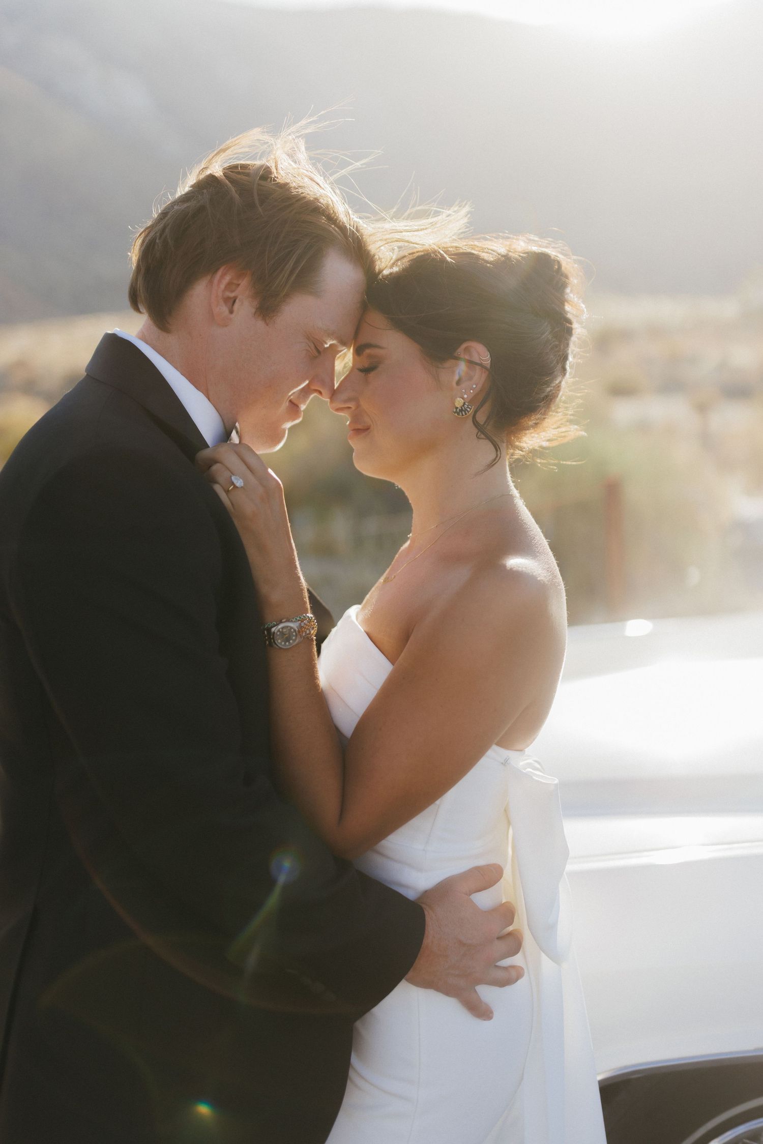 Bride and groom sharing an intimate moment in golden sunset light with mountains in the background.