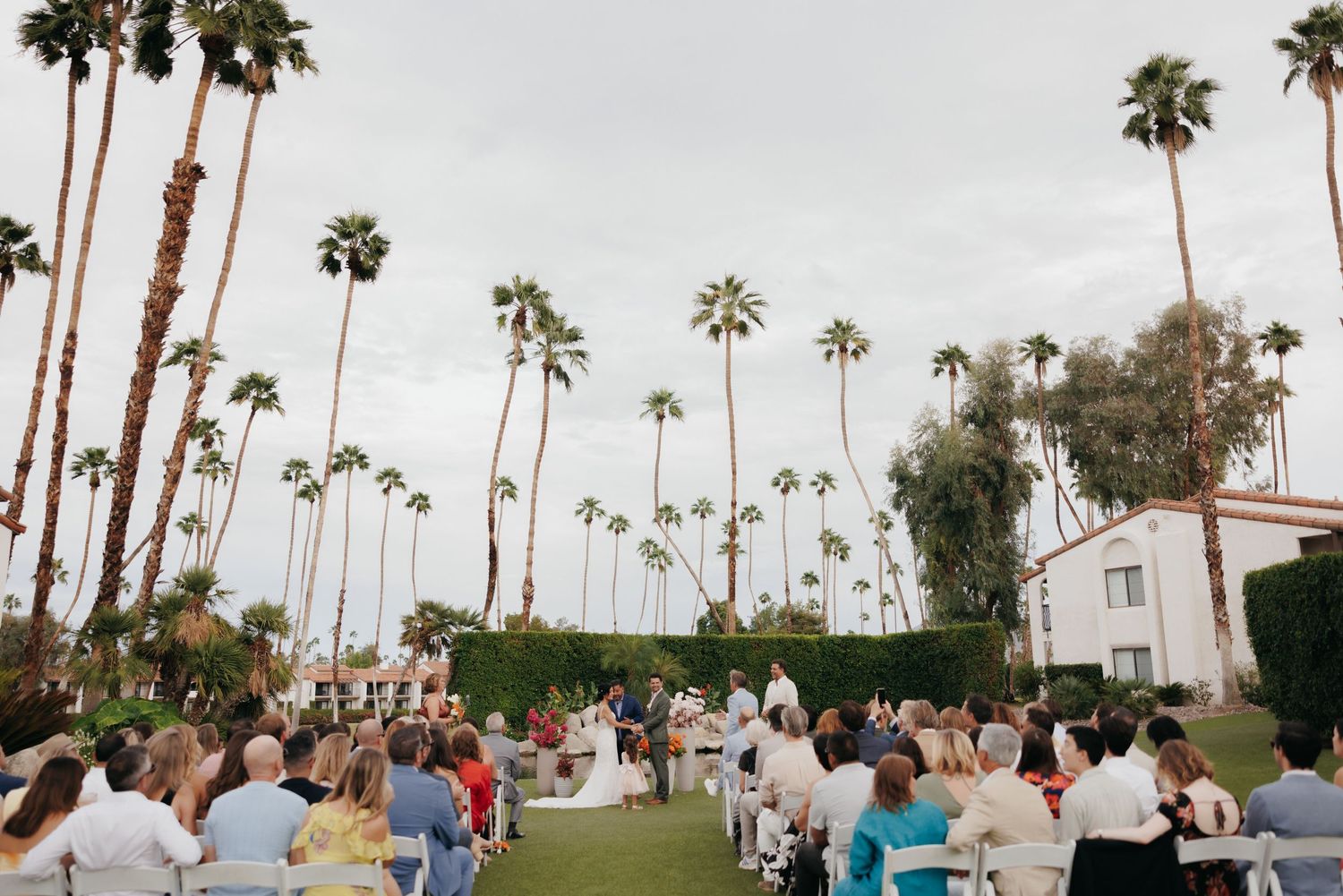 Outdoor wedding ceremony on lush lawn surrounded by tall palm trees at an elegant Palm Springs venue.
