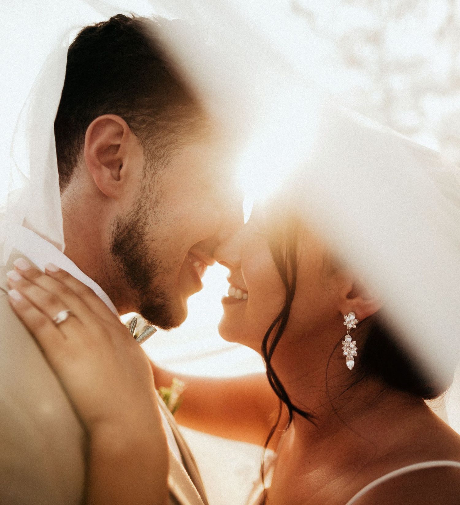 A couple shares an intimate close-up moment in backlit lighting creating a warm, romantic silhouette effect.