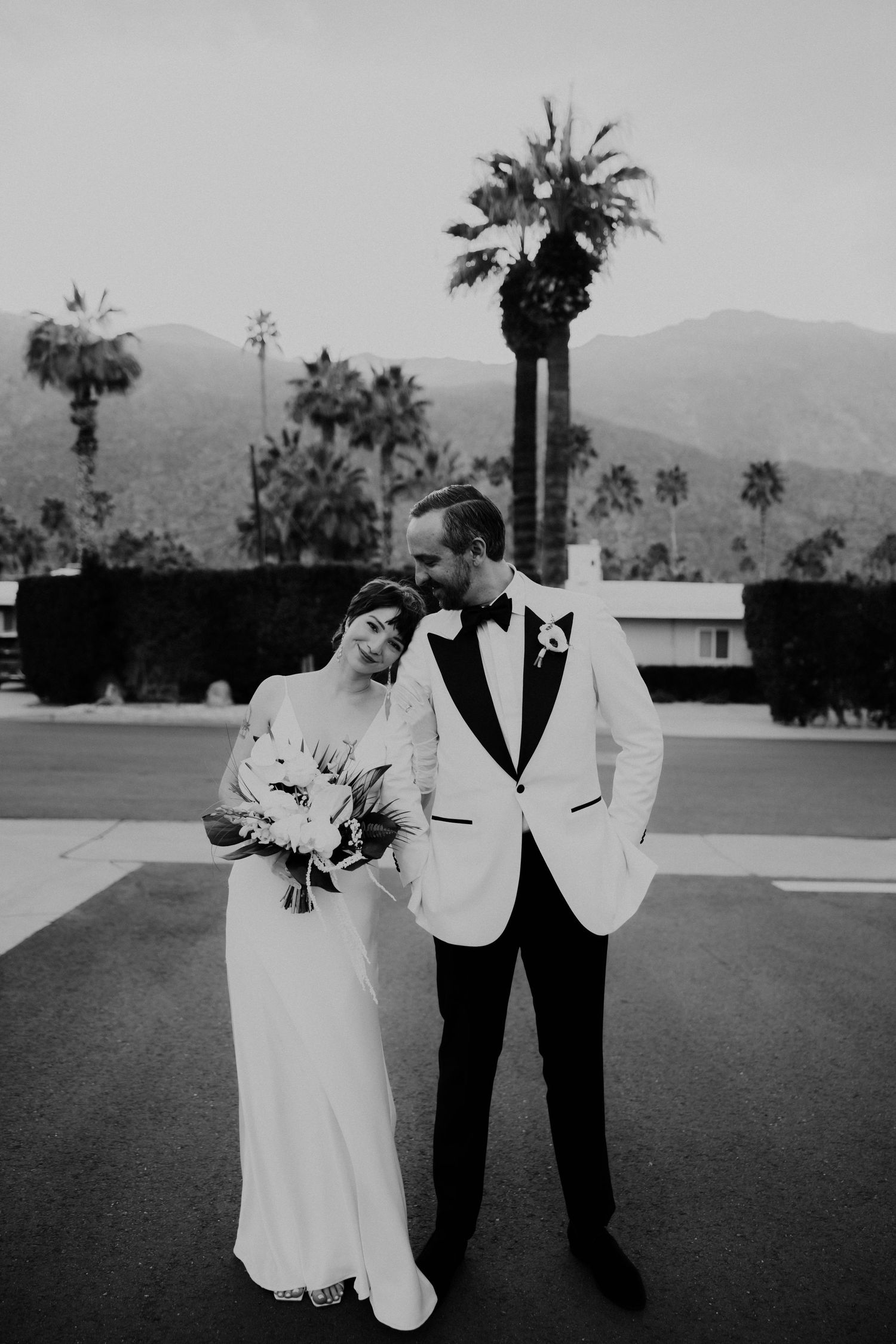 Black and white photos of a couple dancing and celebrating on their wedding day against a palm tree backdrop.