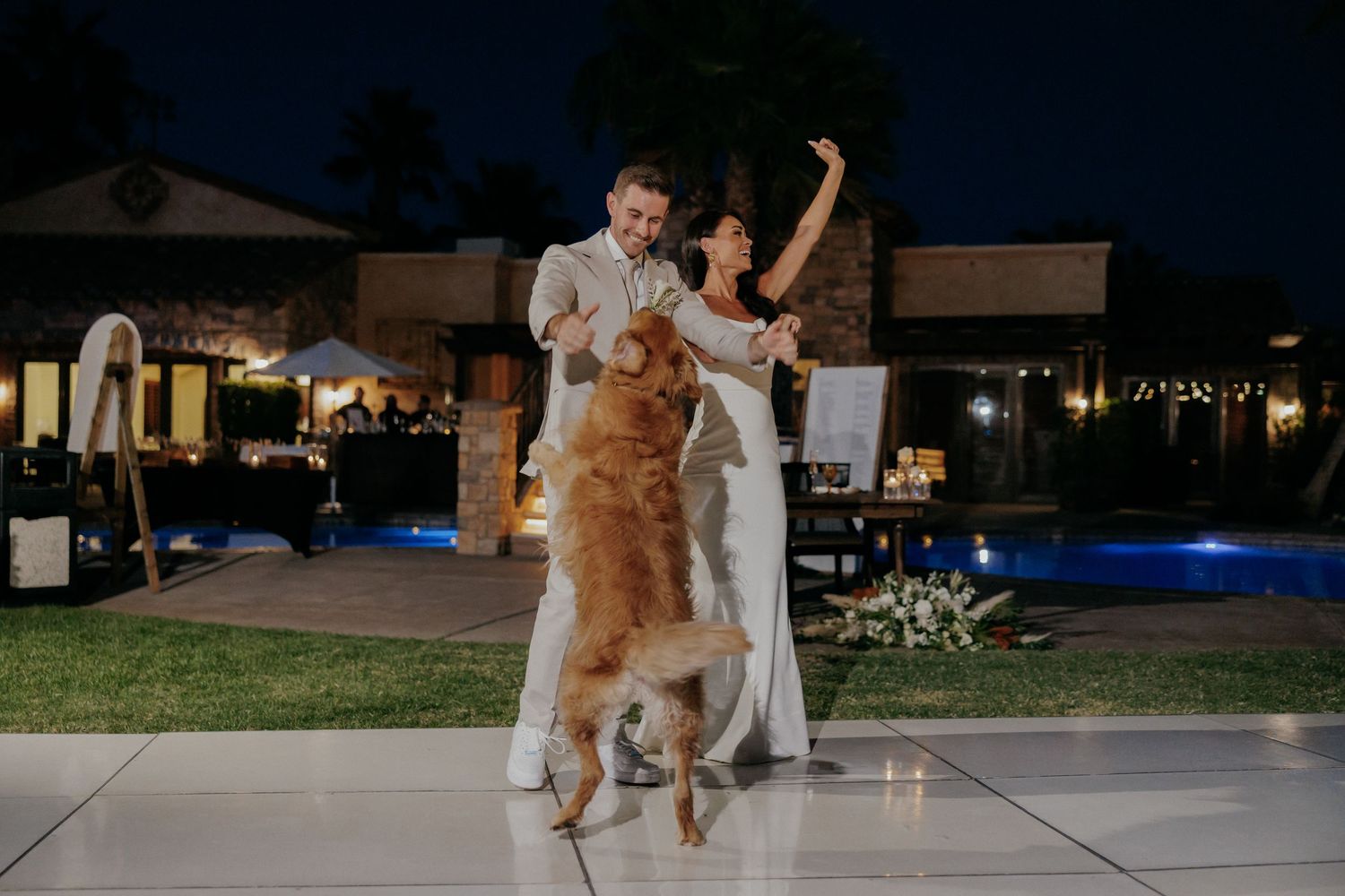 Dog and person dance together on an outdoor patio during an evening celebration.