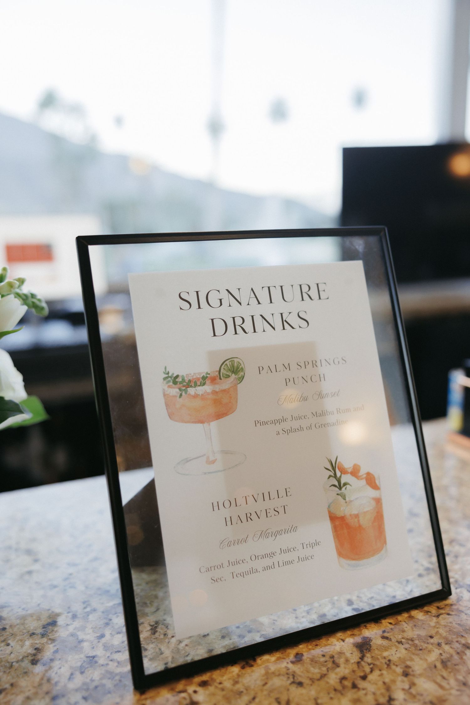 Framed signature drinks menu displaying Palm Springs Punch and Holtville Harvest cocktail options.