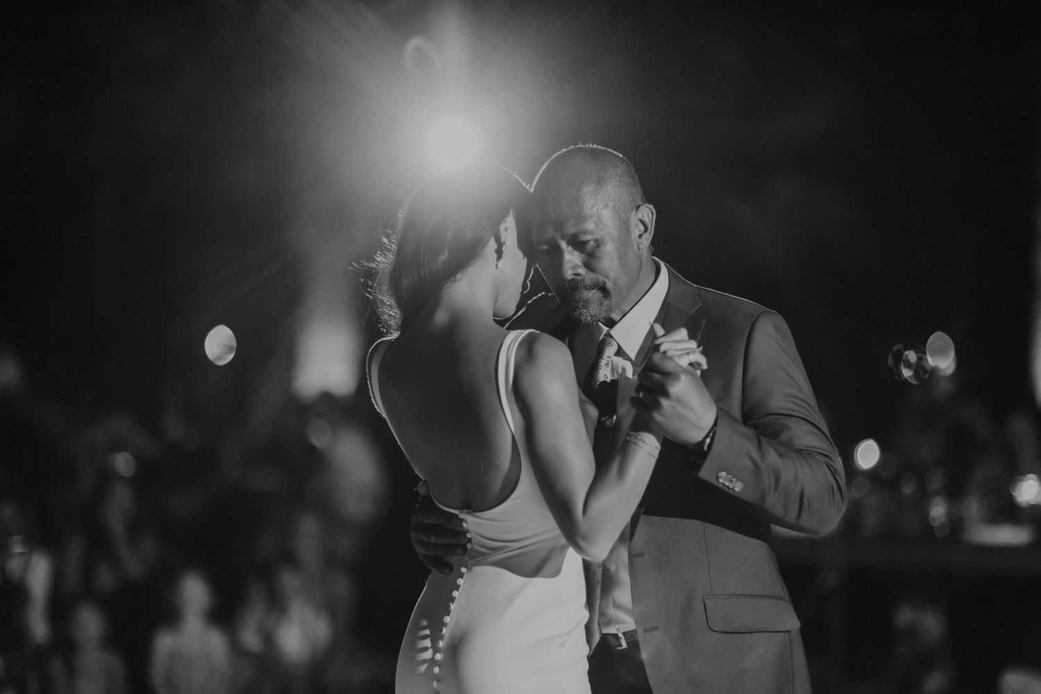 Loving couple embraces and dances together during their wedding reception in black and white.