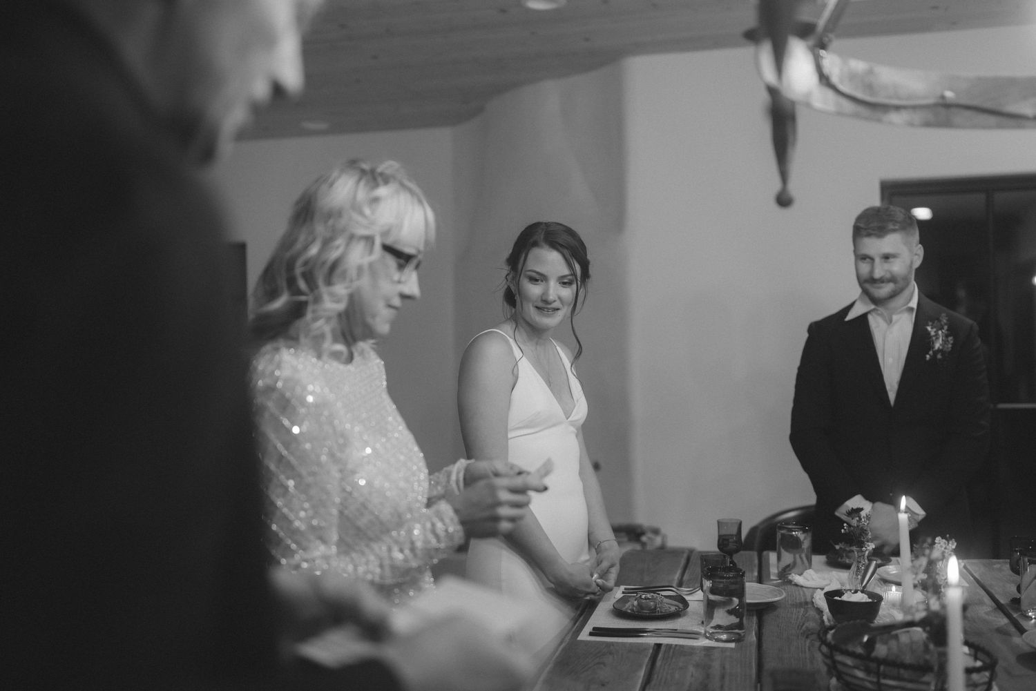 Black and white photo of bride smiling during indoor wedding ceremony with candles.