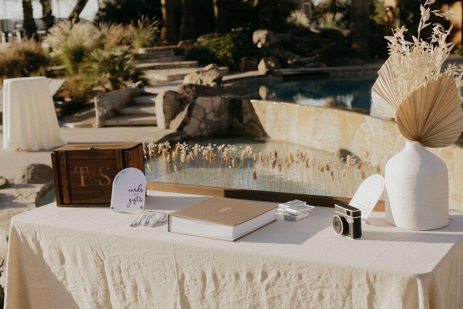 A wedding ceremony setting with white parasols and elegant white decor arranged outdoors in a natural landscape.