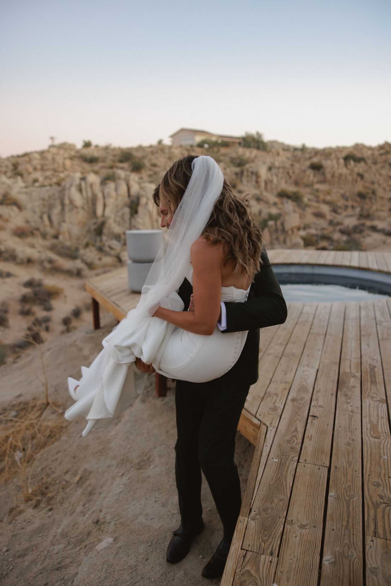 Person in black clothing dances with flowing white fabric against desert landscape backdrop.