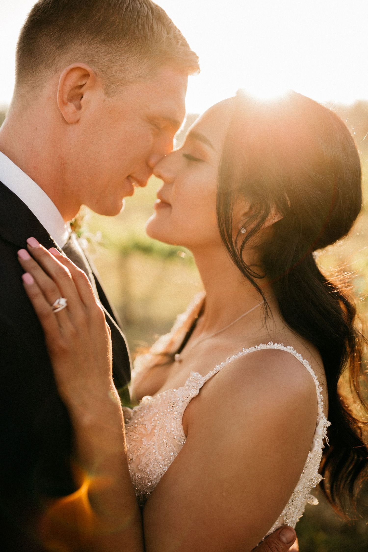 Romantic sunset portrait of a couple in wedding attire with golden backlighting.