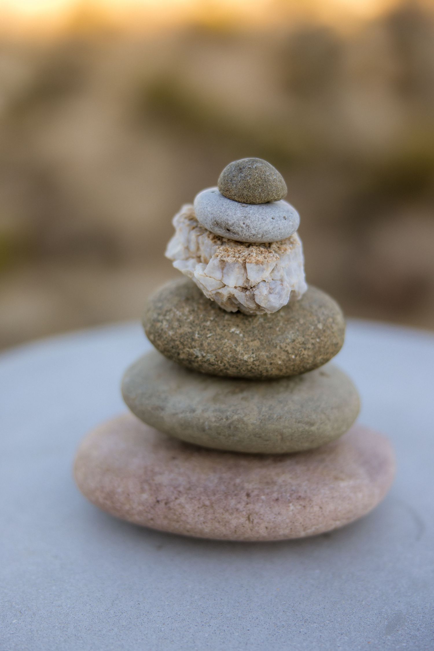 Close-up of balanced stone cairn with frosted or icy layers stacked in harmony against blurred natural background.