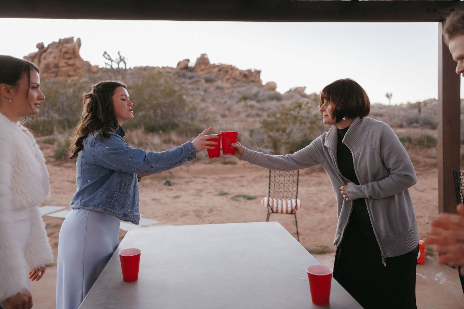 Two wedding guests toasting with red Solo cups at an outdoor desert wedding reception celebration.