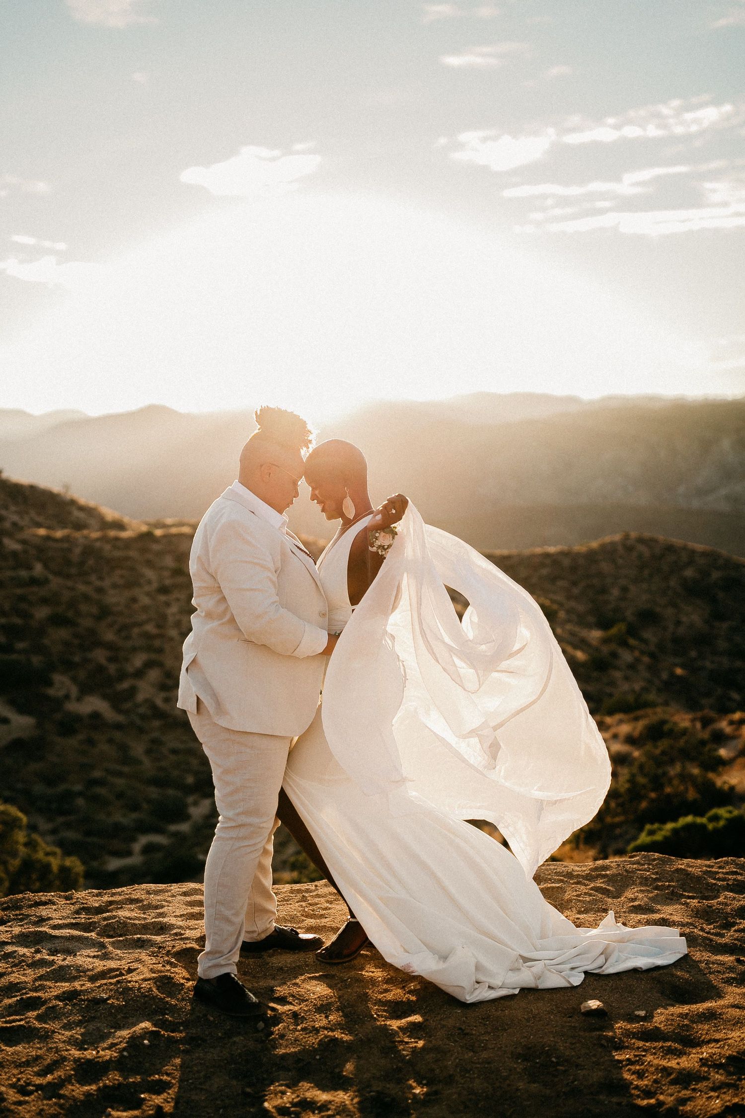 A romantic sunset wedding photo shoot on rocky terrain with flowing white attire.