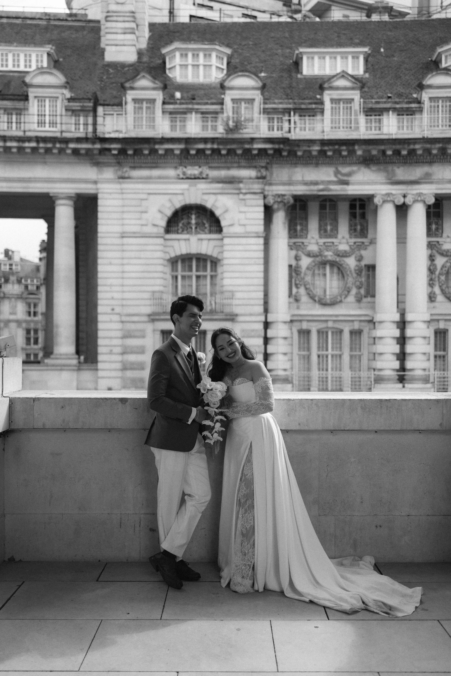 Four sequential black and white photos show a romantic moment between a couple on a balcony of an elegant building.