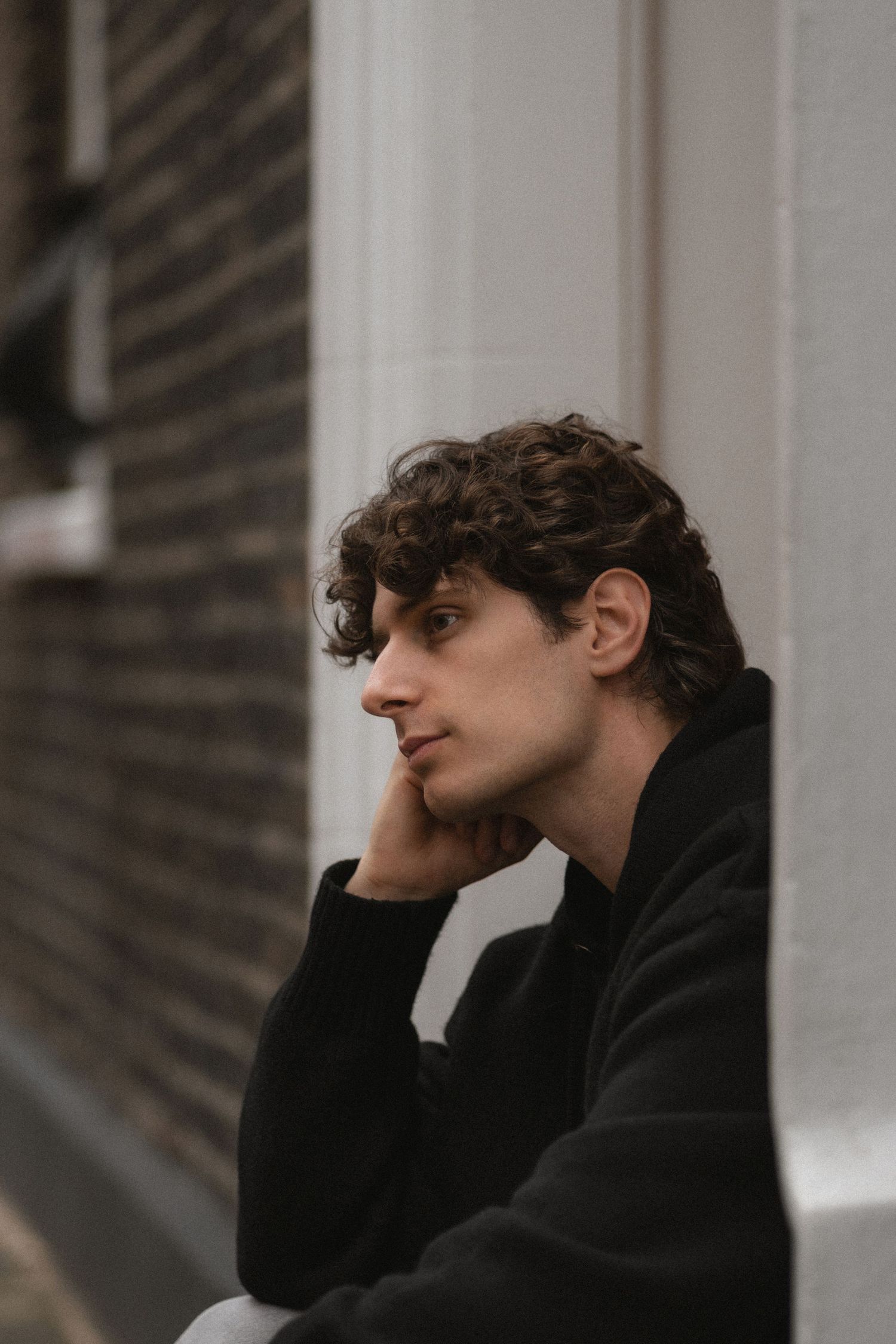 A person in a black sweater sits in profile view against a blurred background in a series of similar poses.