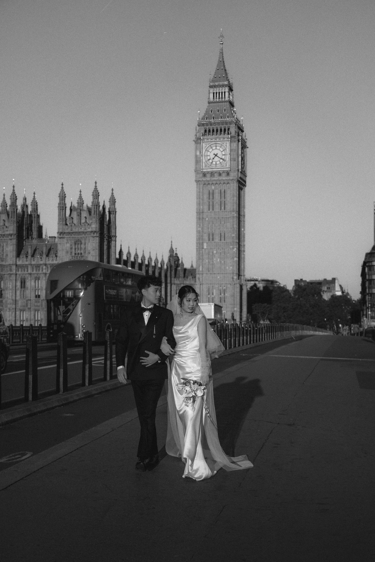 Couple in wedding attire posing in front of Big Ben and Houses of Parliament in London, black and white photo.