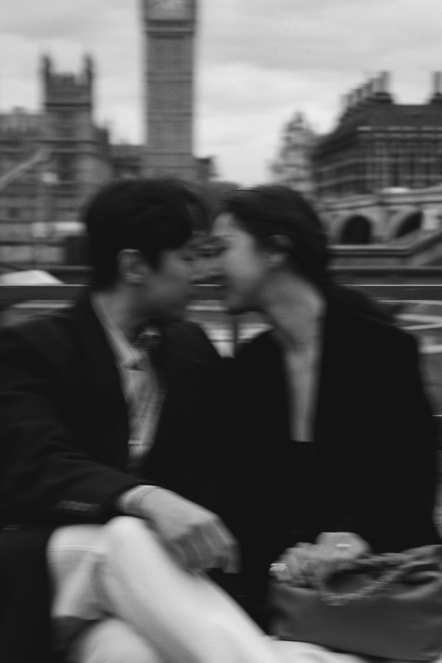 A romantic black and white photo sequence showing a couple embracing and kissing on a city bridge.