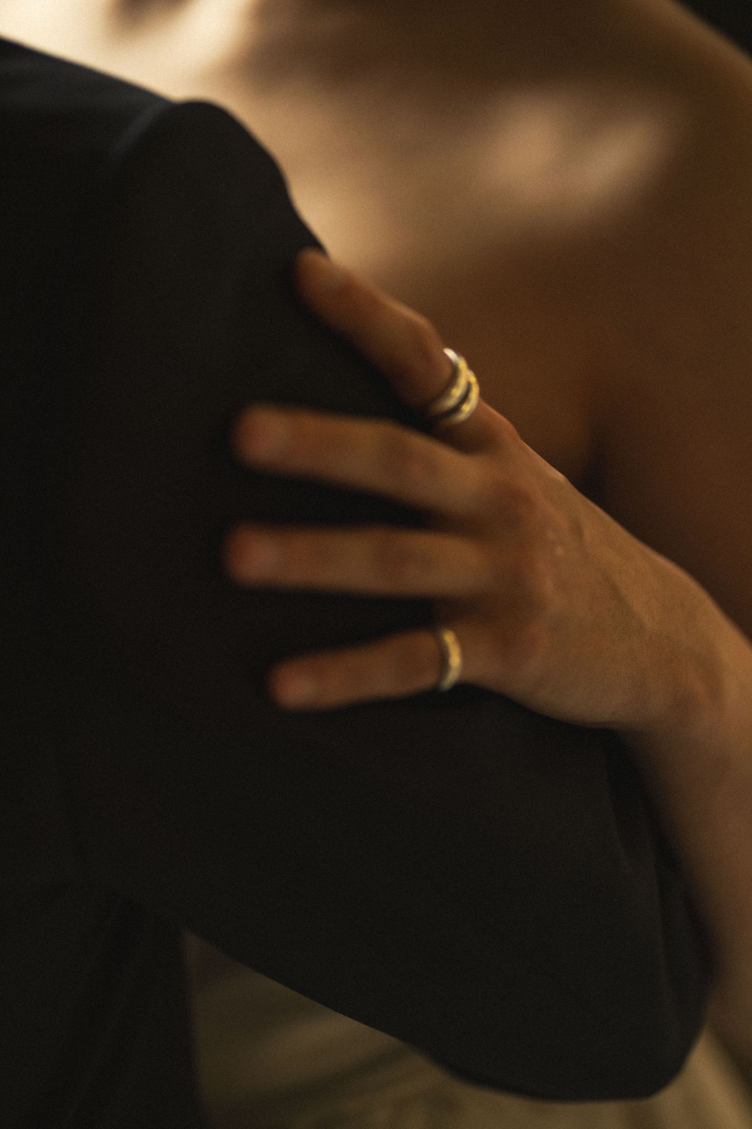 Close-up shot of hands wearing gold rings against a dark background.