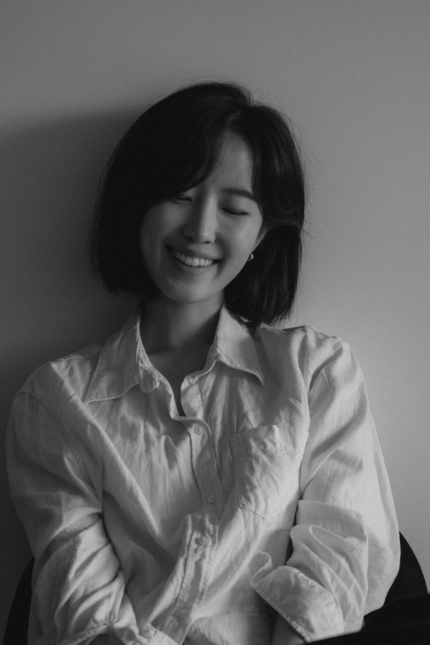 Portrait of person in white shirt smiling warmly against neutral background.