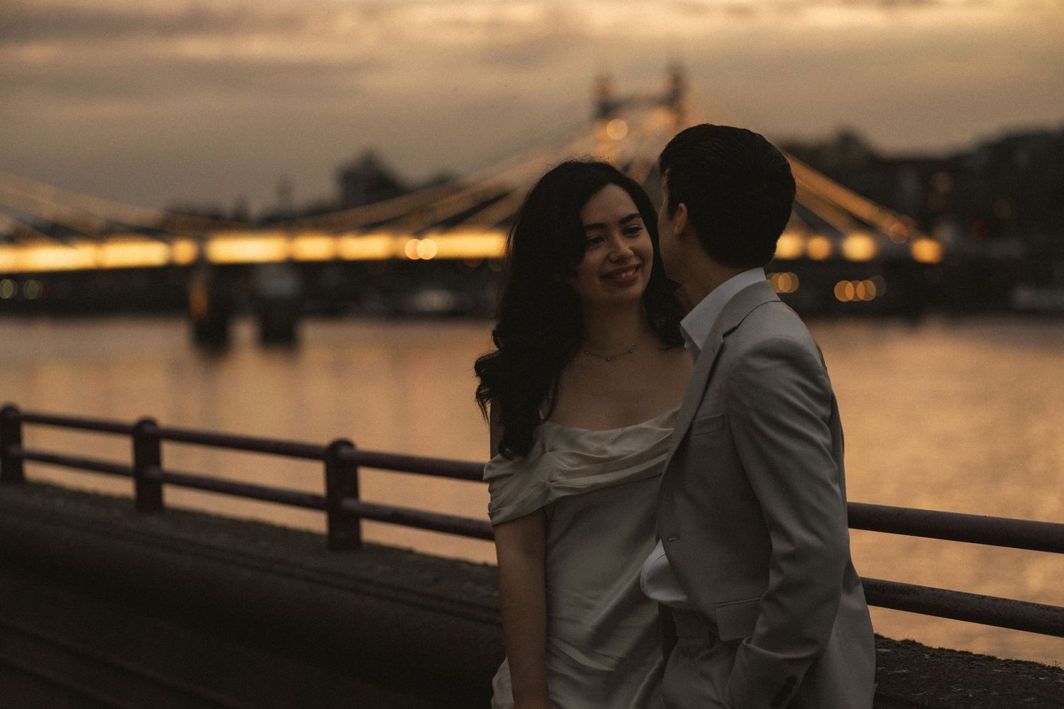 Couple embraces at sunset by a waterfront pier creating a romantic silhouette against the golden sky.