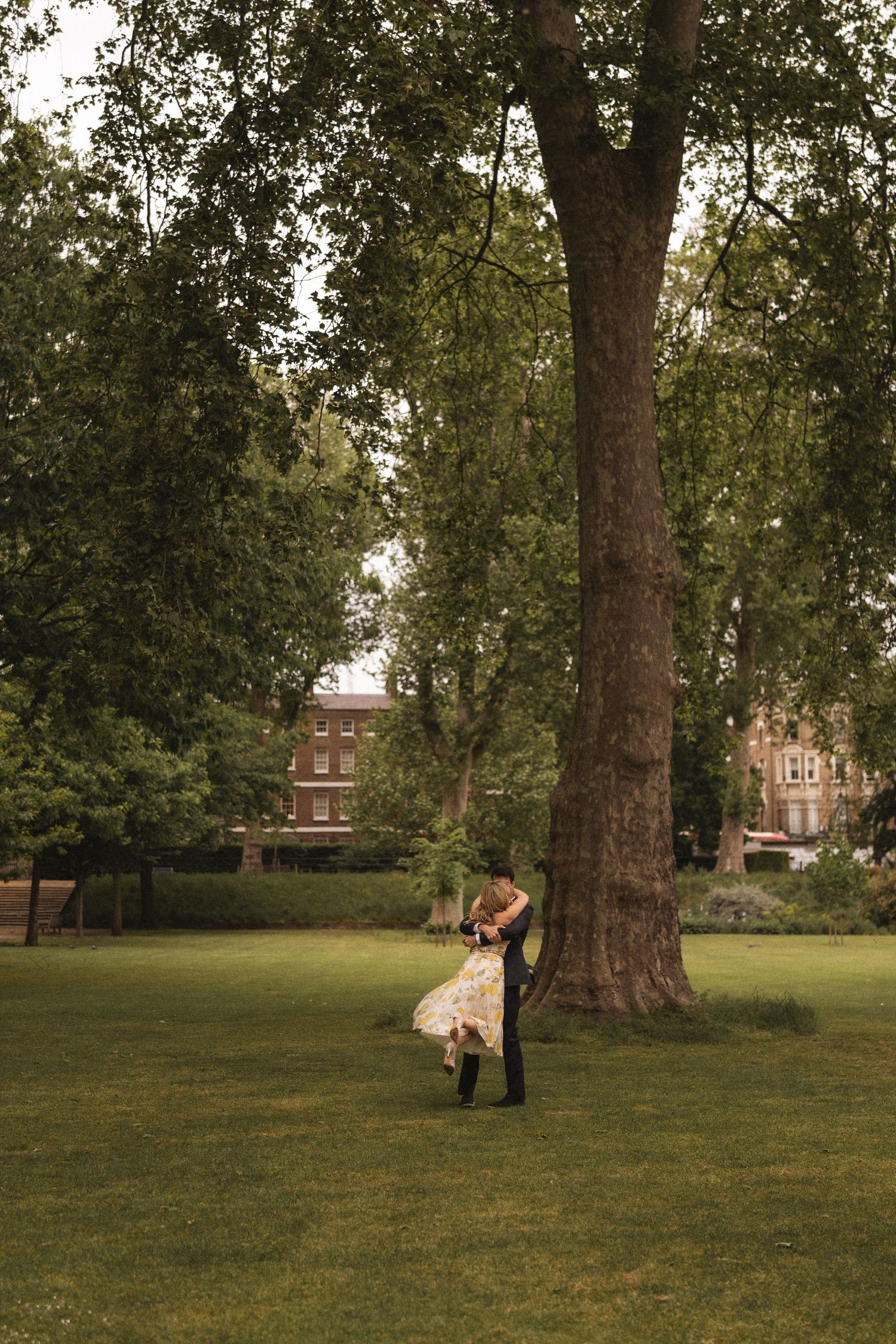 A series of four photos showing a couple in a romantic engagement photoshoot on a grassy lawn with trees and buildings.