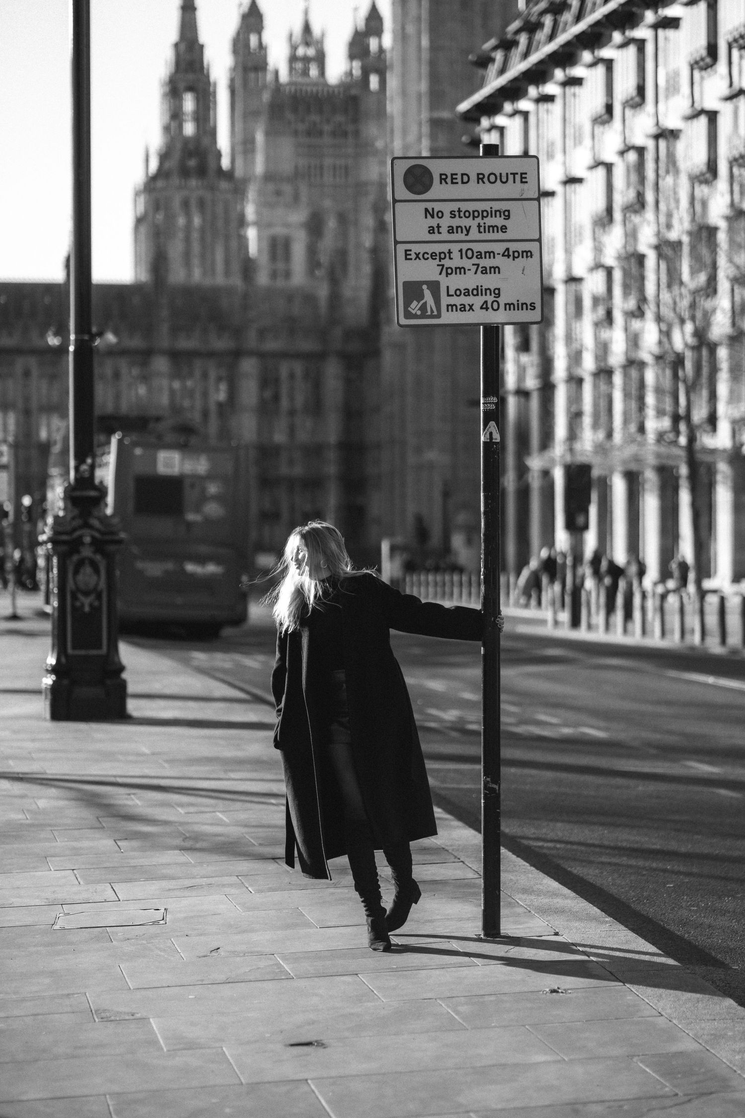 A person walks down a historic street with gothic architecture and dramatic shadows in black and white photography.