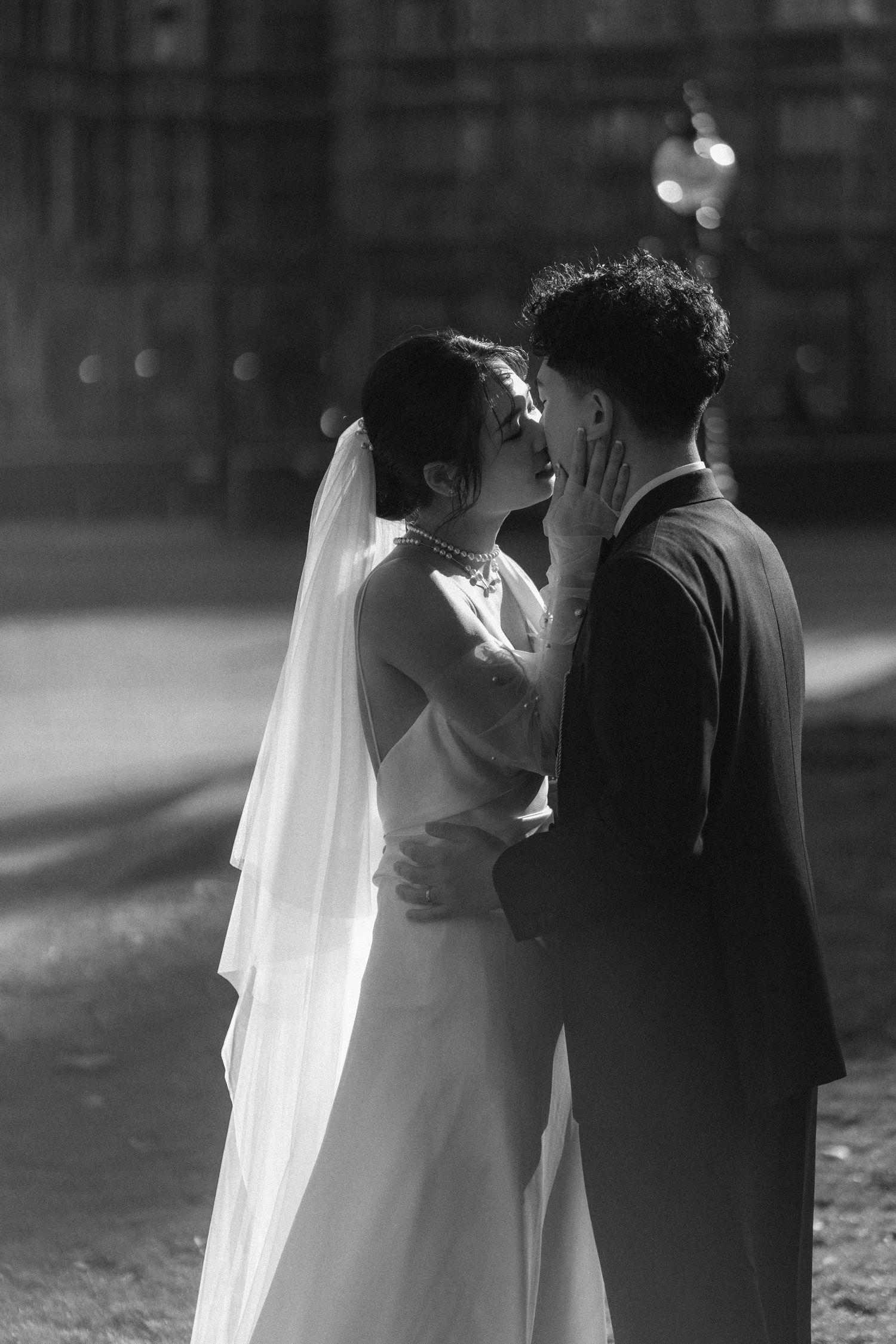 Black and white photo of a bride and groom sharing a romantic kiss on their wedding day.