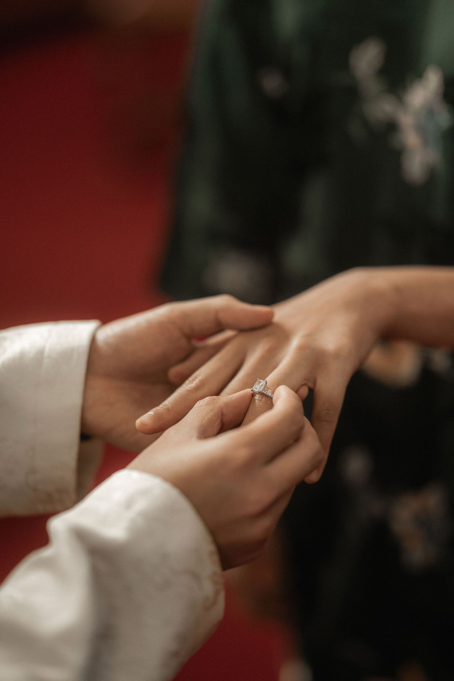 Close-up of a groom placing a diamond engagement ring on his bride's finger during a wedding ceremony.