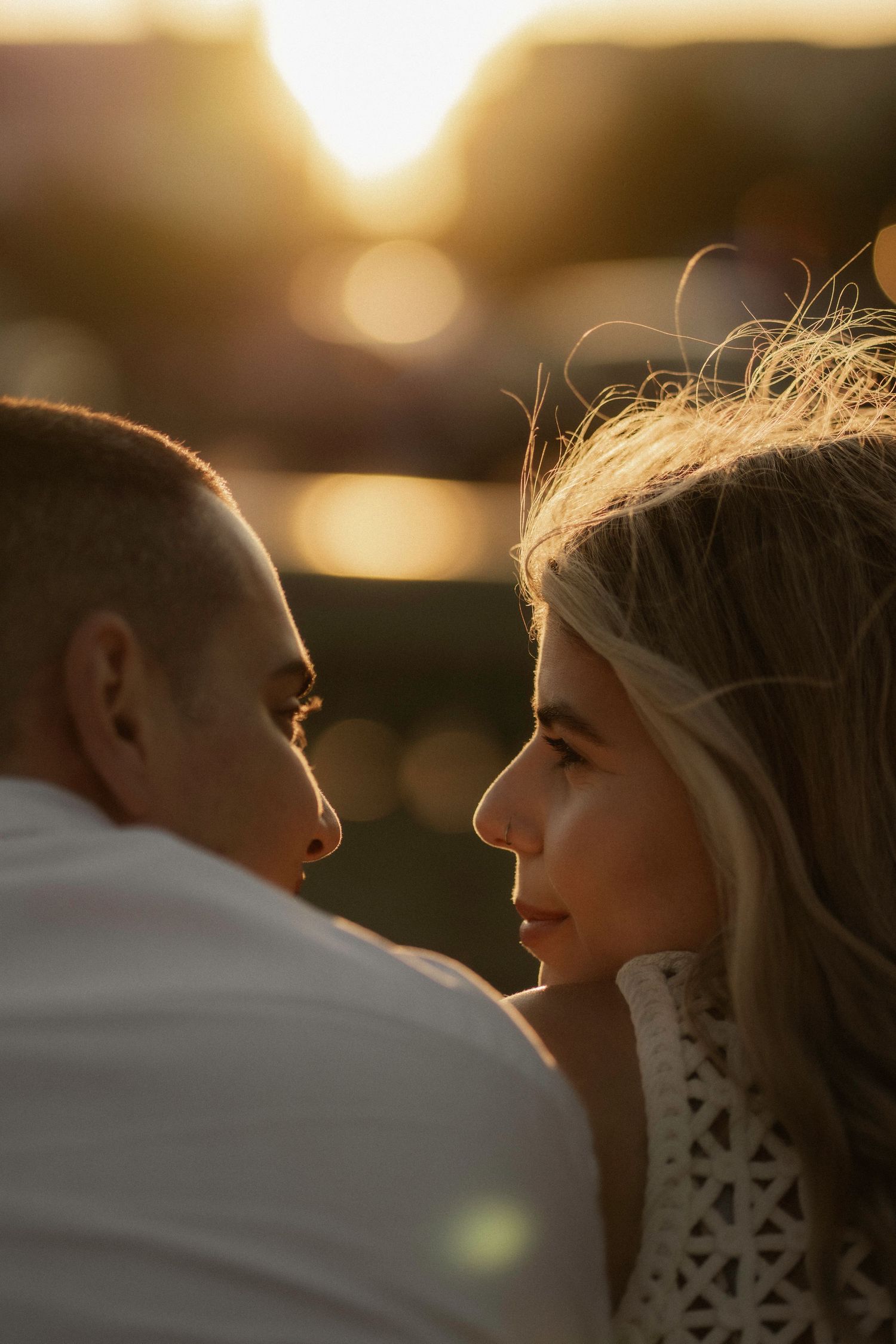 A romantic couple silhouetted against a golden sunset share an intimate moment in a series of connected photos.