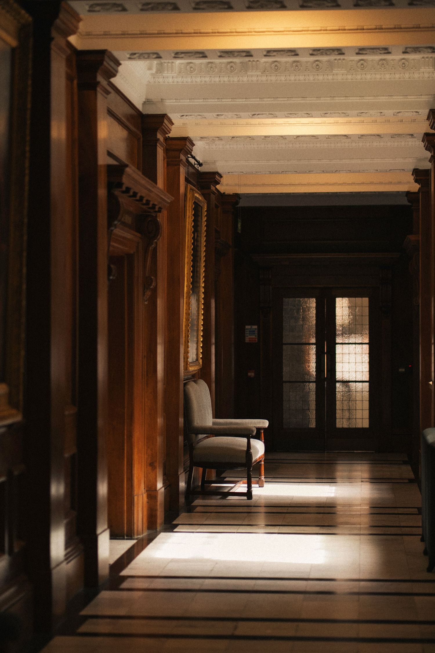 Dimly lit traditional Japanese temple corridor with wooden pillars and natural light filtering through the windows.