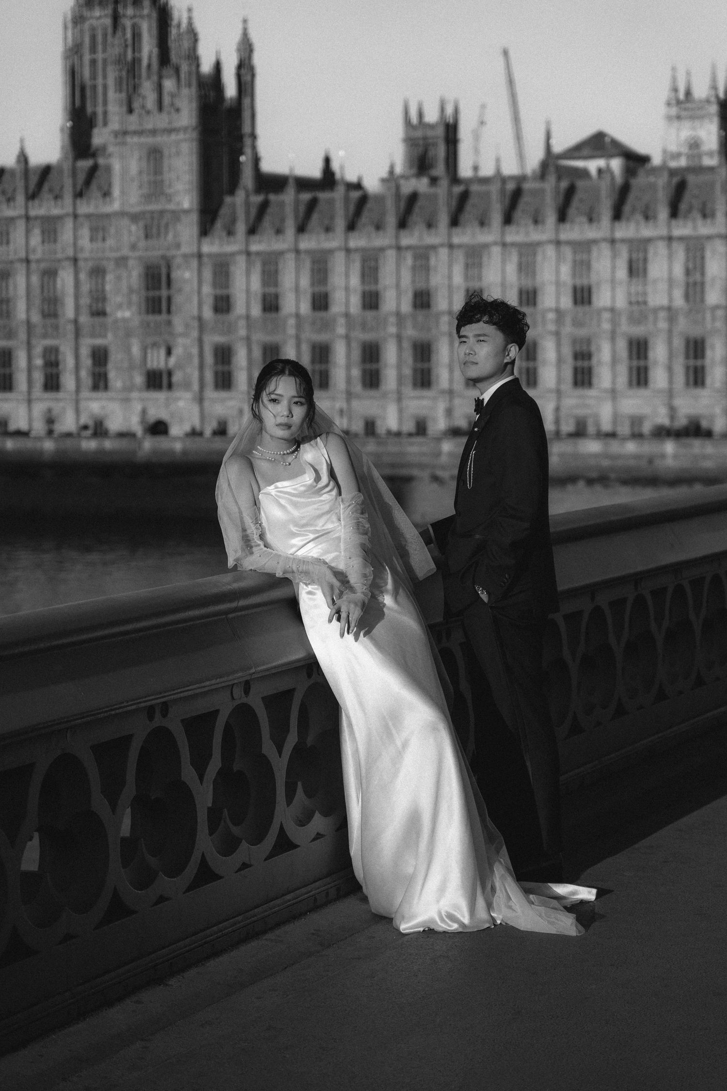 Black and white wedding photo of a couple posing on Westminster Bridge with the Houses of Parliament in the background, London.