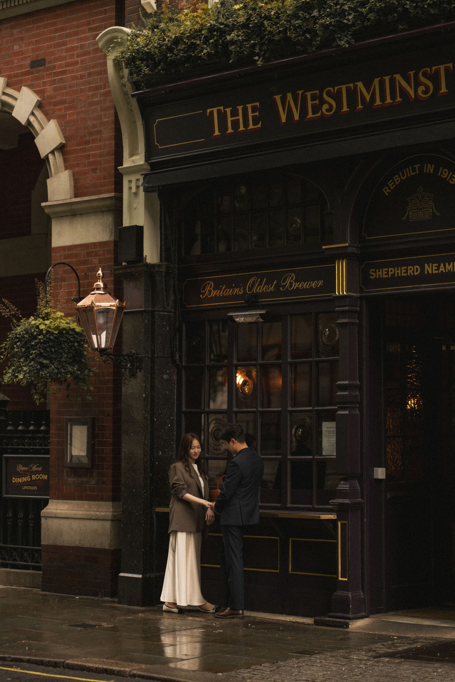 A couple stands outside a vintage brick building with 'The Westminster' signage in moody evening lighting.