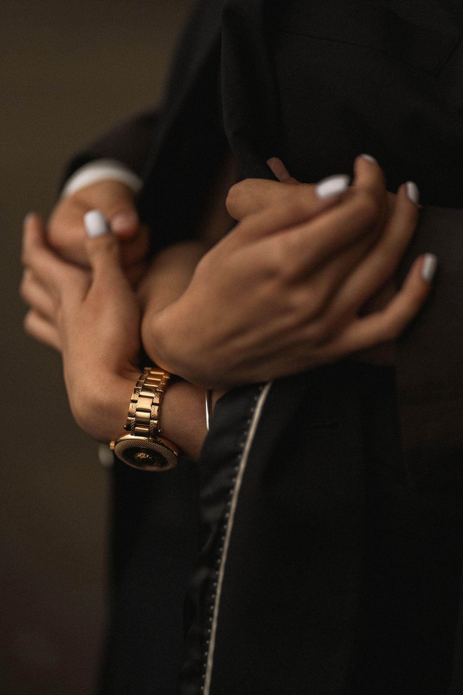 Close-up shot of a gold watch on someone's wrist against a dark background with dramatic lighting.