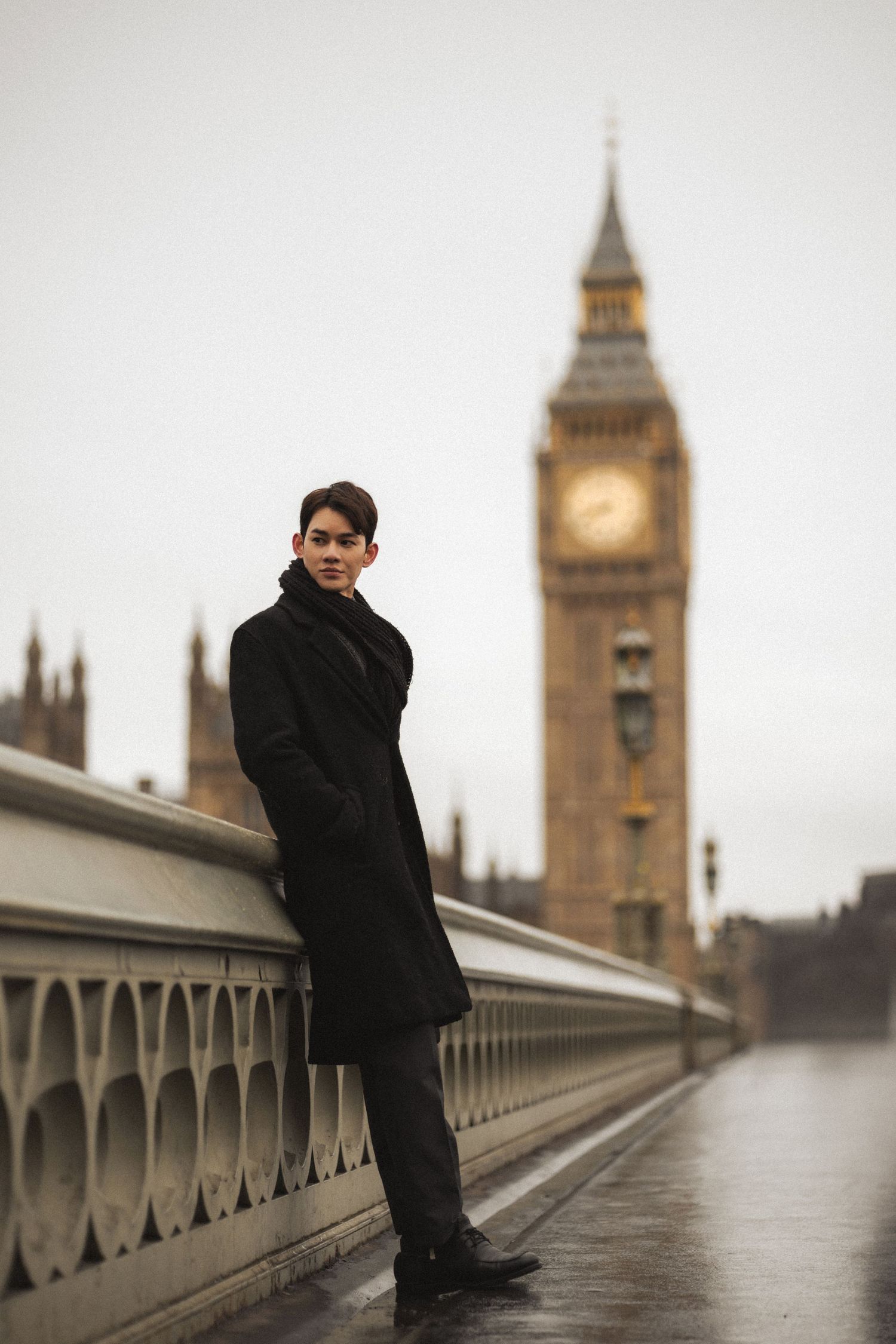 A person in dark clothing stands on Westminster Bridge with Big Ben and Parliament visible in the misty London backdrop.