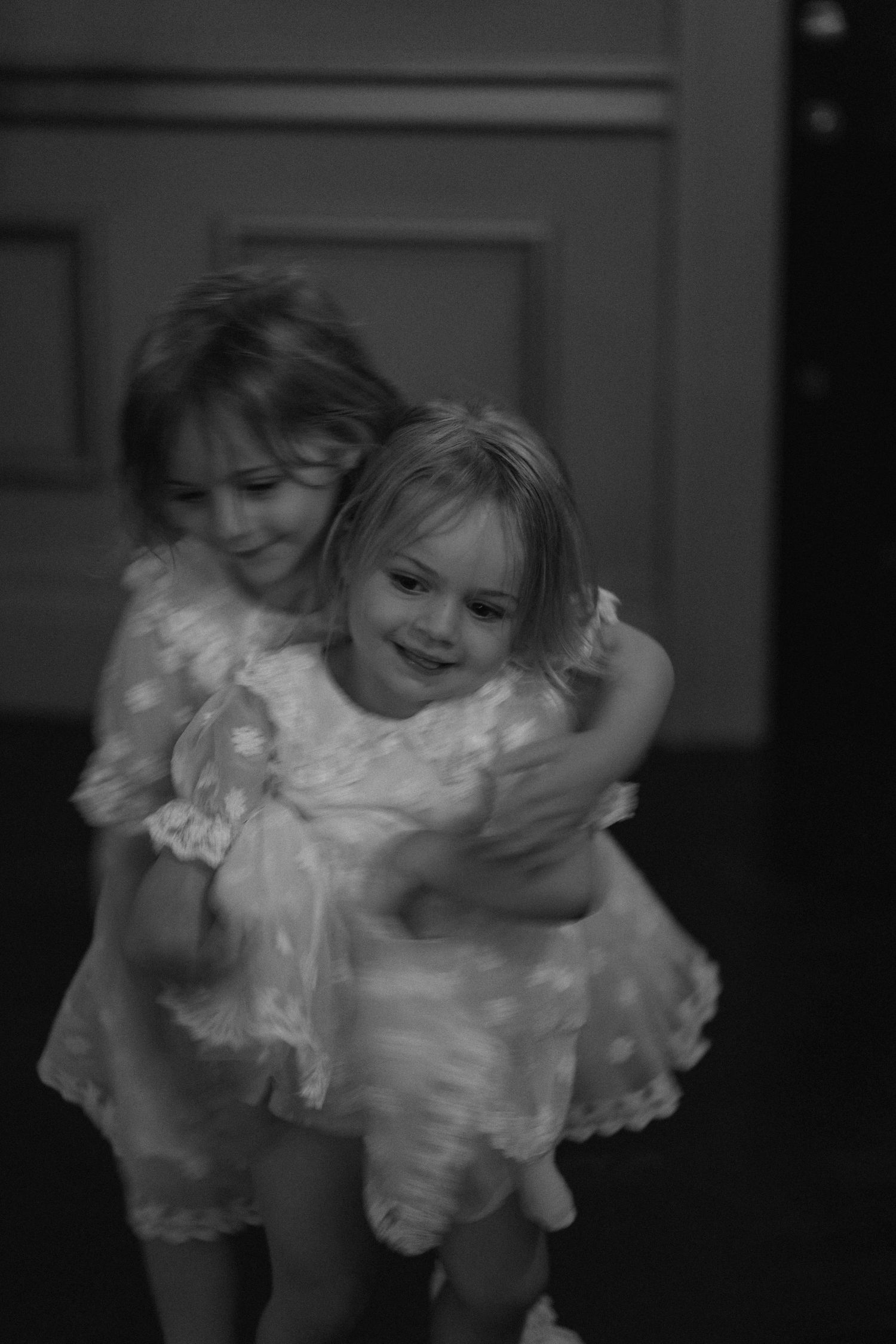 Black and white photo series showing a child in a white ruffled dress twirling and dancing with joyful movement.
