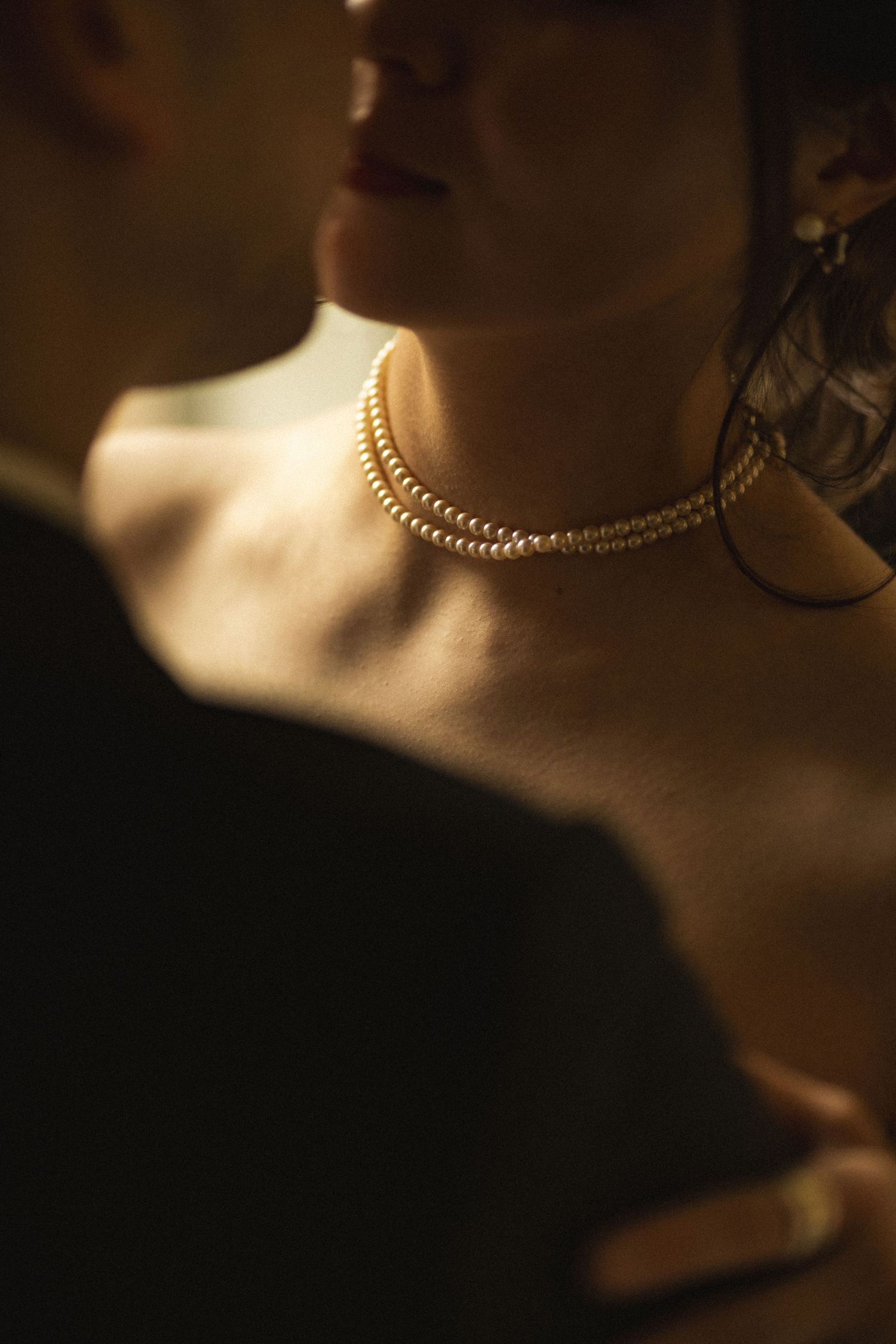 Close-up view of a delicate gold chain necklace against a dark background with dramatic lighting.