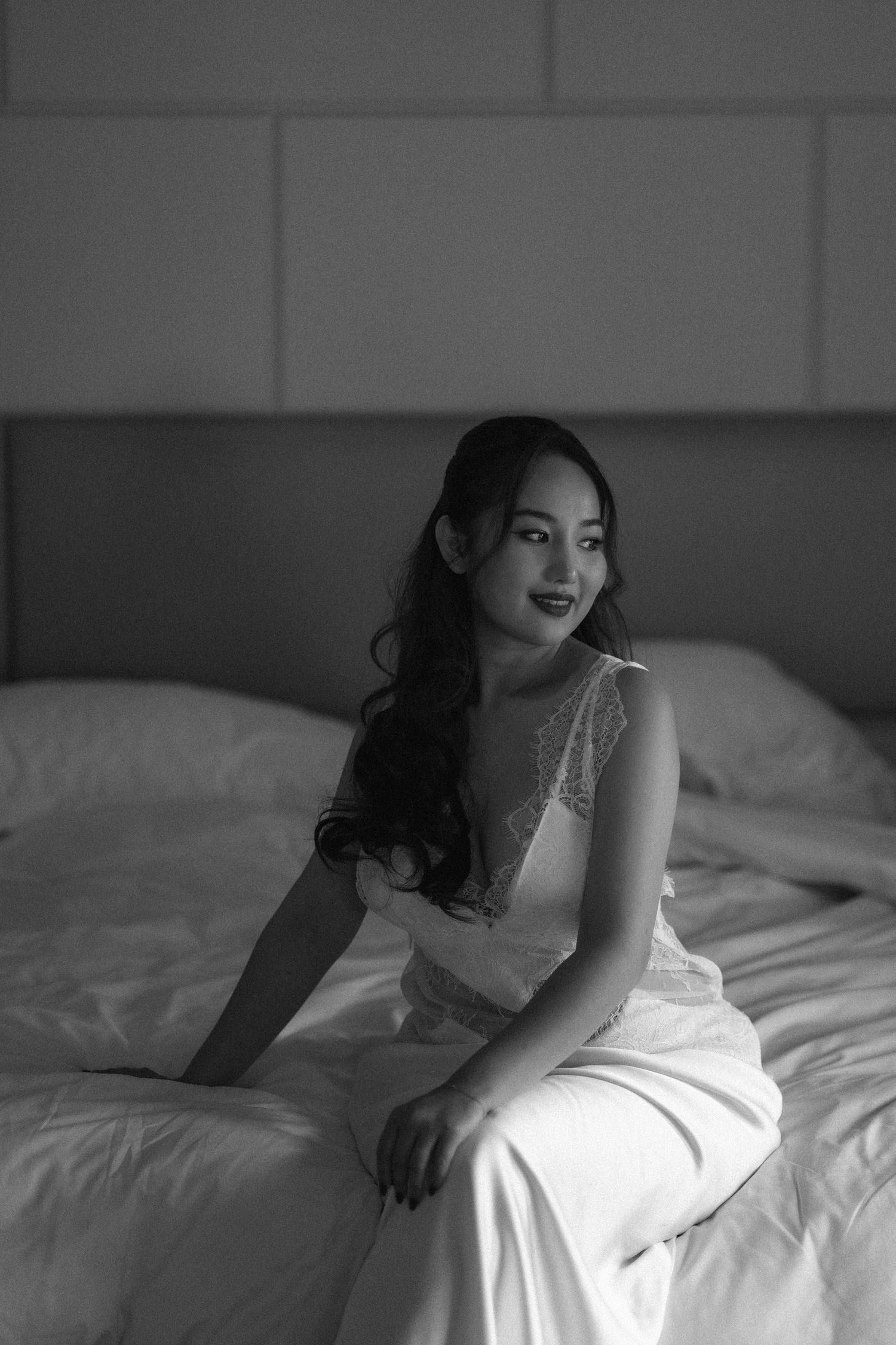 Black and white boudoir photography series showing a woman in white lingerie posing elegantly on a bed.