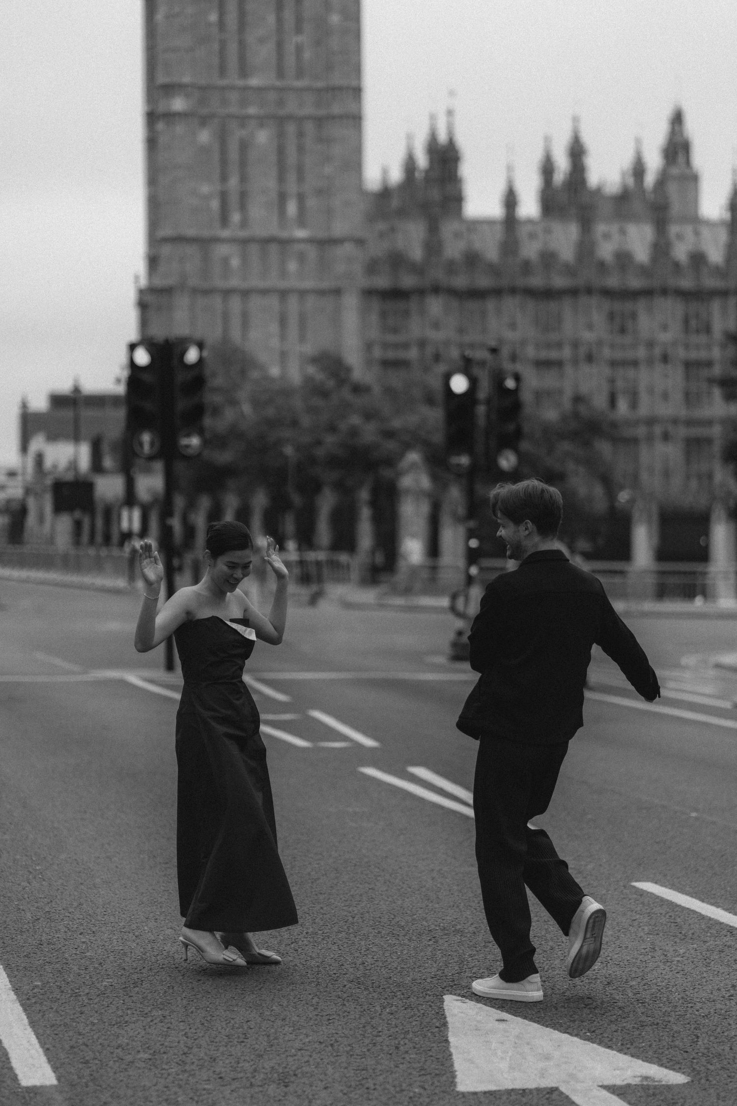 Two silhouetted figures run playfully across Westminster Bridge with Big Ben and Parliament in the background.