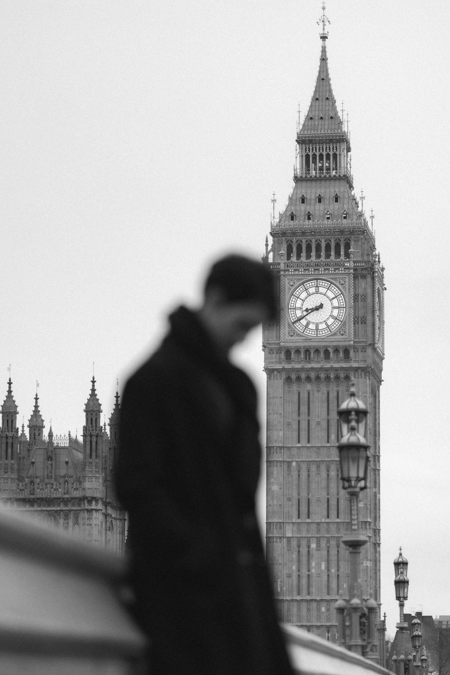 Silhouetted figures stand against the iconic Big Ben clock tower in London creating a romantic black and white scene.