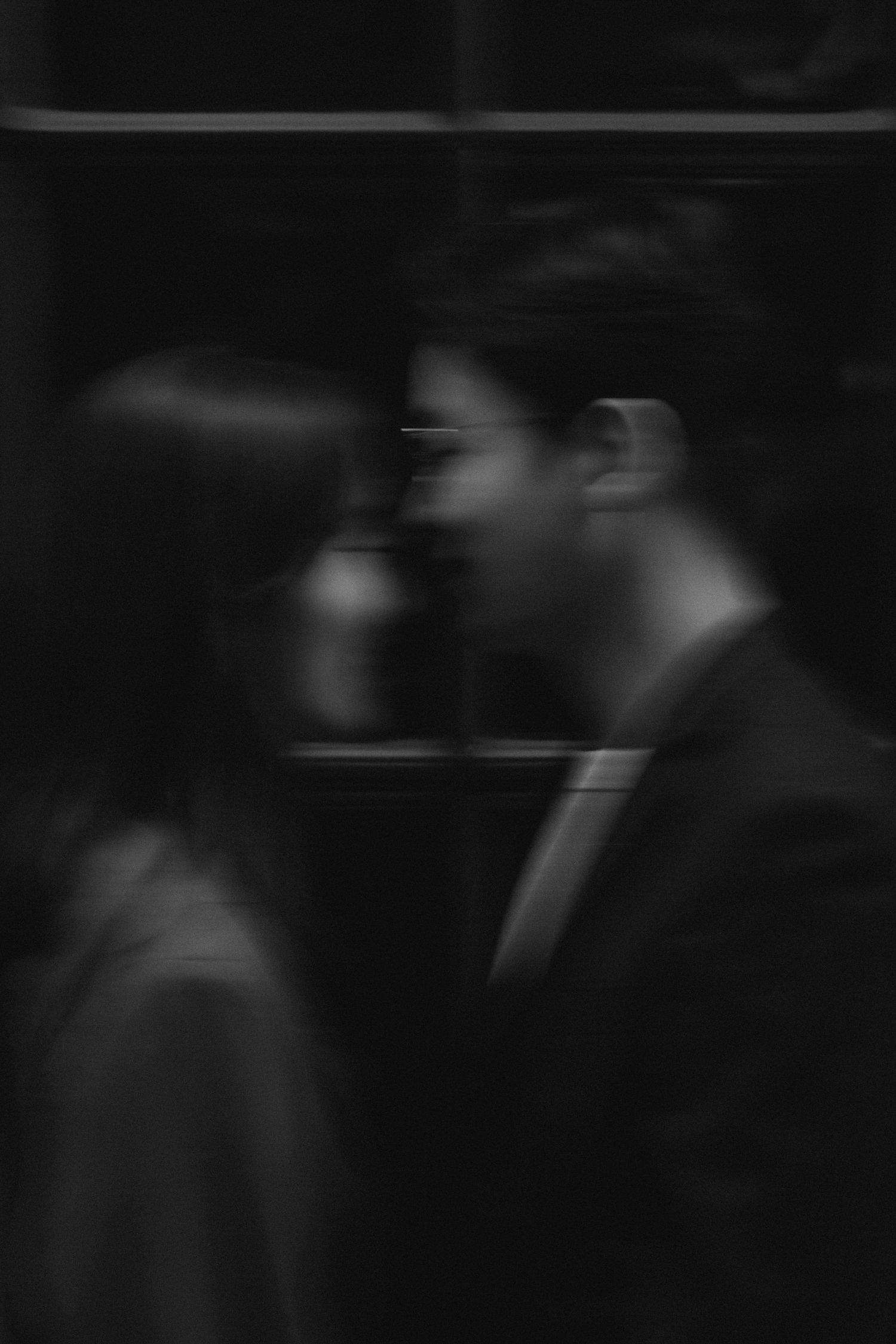 A blurry black and white photograph shows several figures walking in shadows creating a film noir atmosphere.