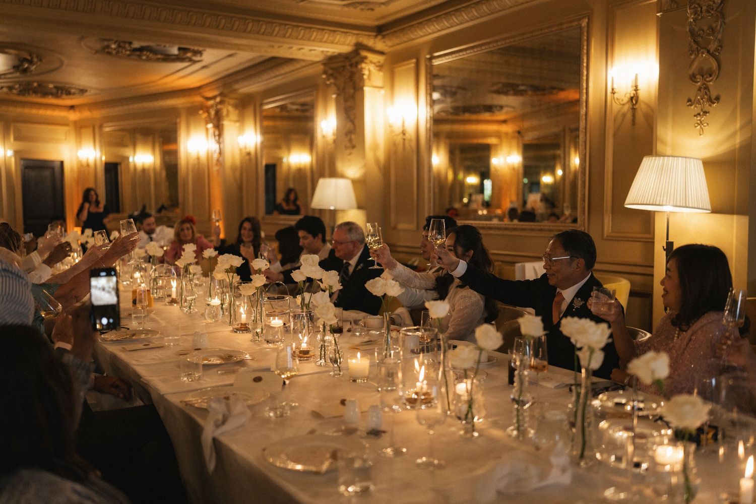 Elegant banquet hall with ornate decor, warm lighting, and multiple tables set for a formal dining event.