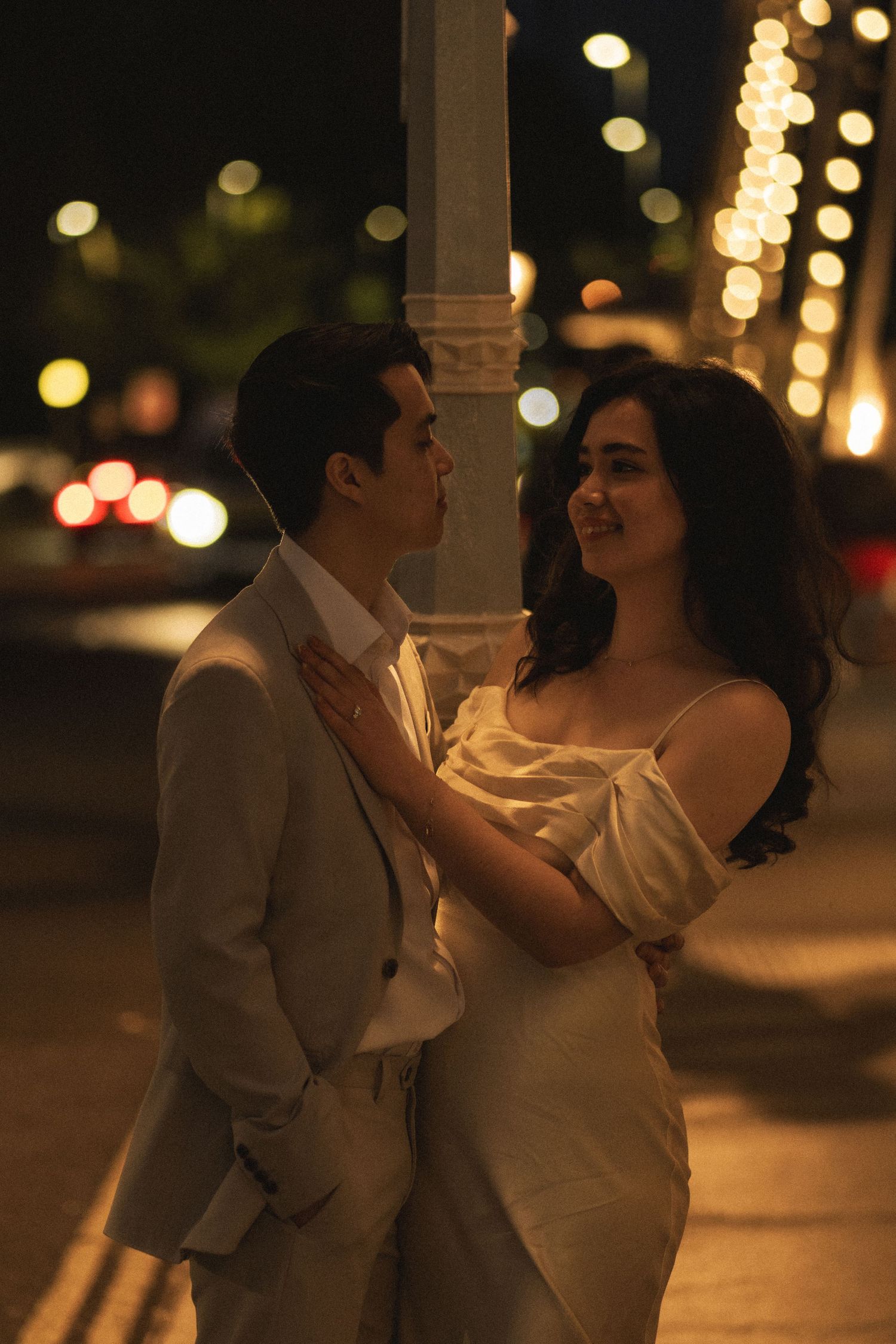 A couple shares a romantic dance together at night under warm glowing lights creating an intimate atmosphere.