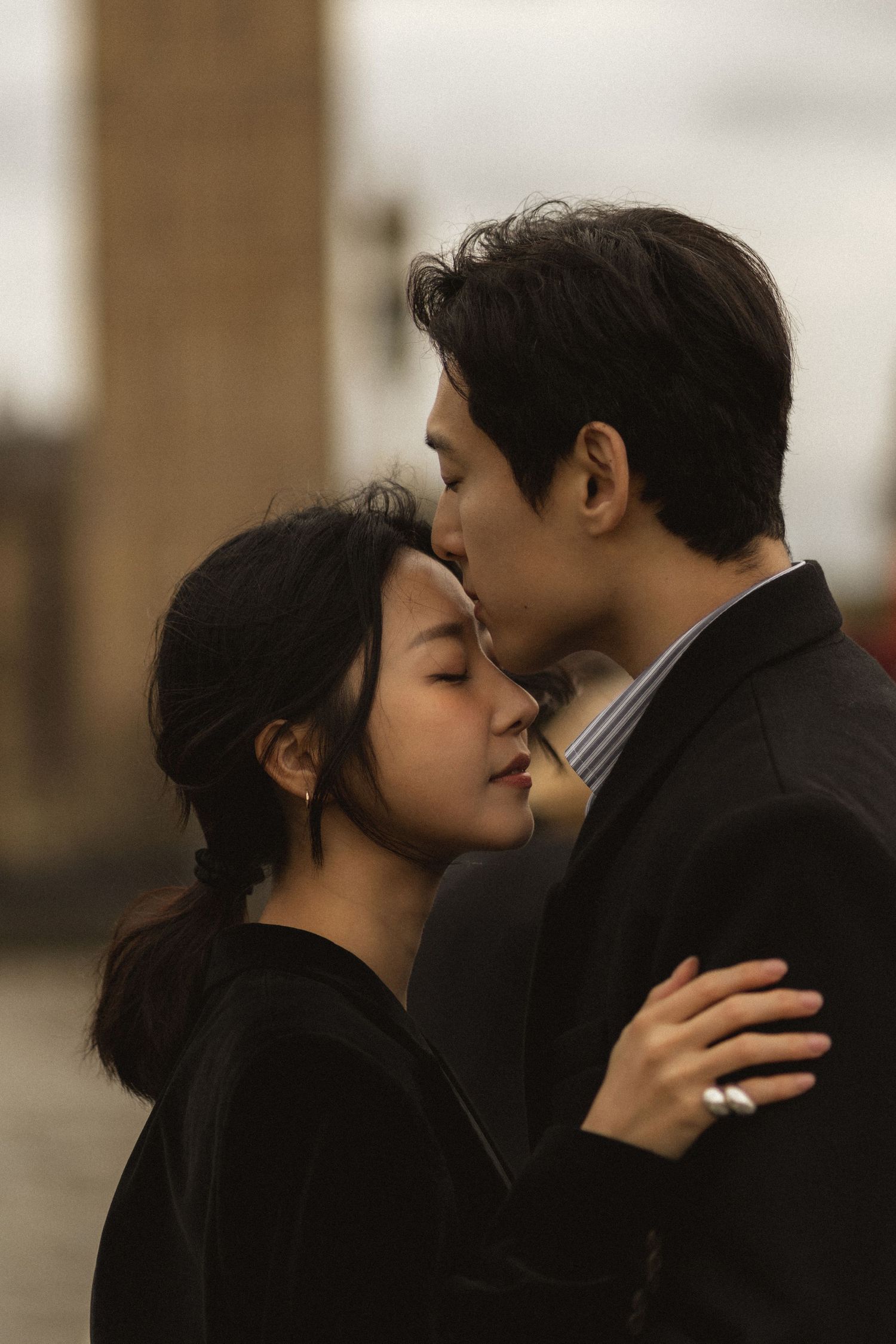 A romantic couple in black clothing share intimate kisses in a series of sepia-toned photographs.
