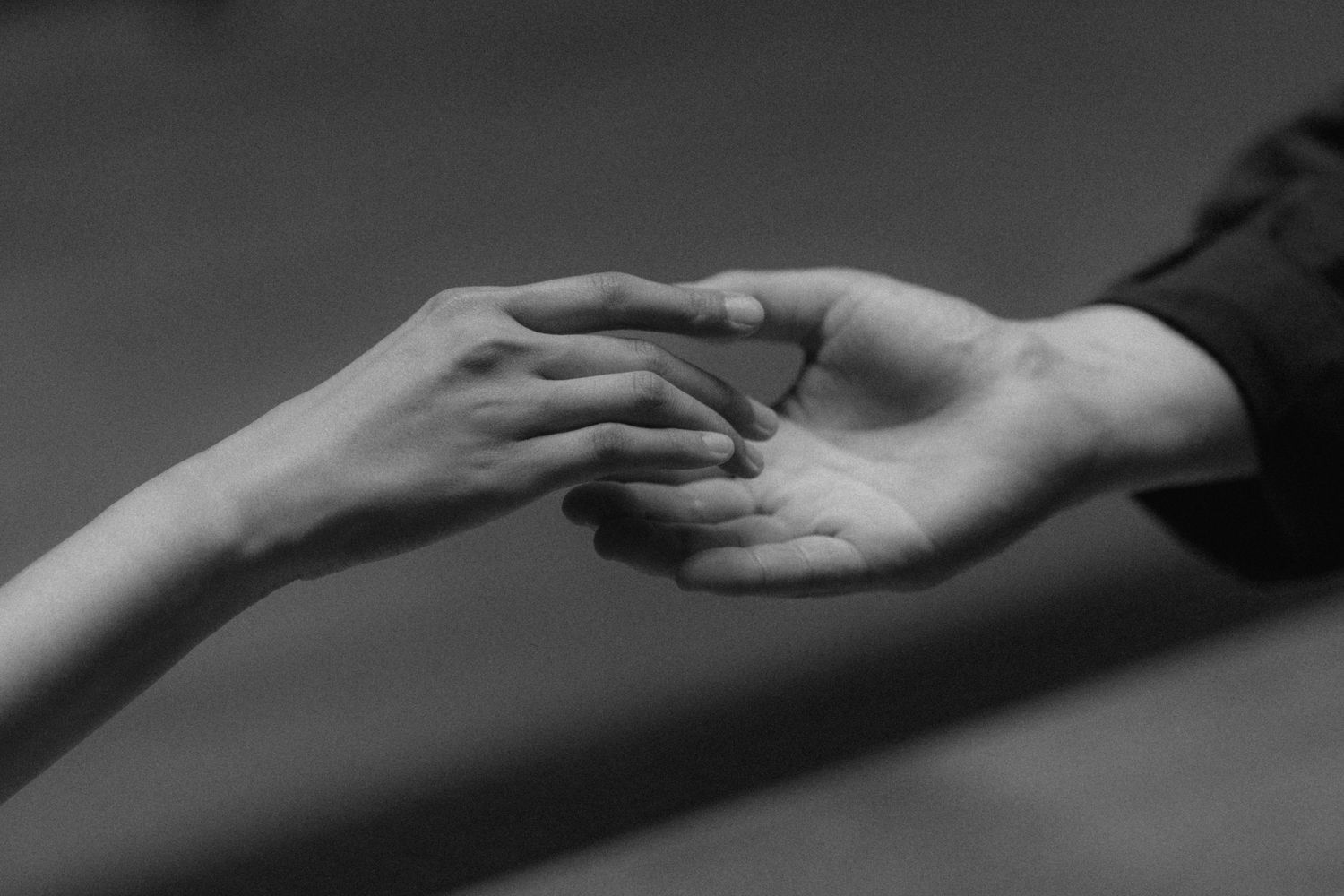 Black and white sequence of hands reaching out and connecting with each other in a graceful motion.