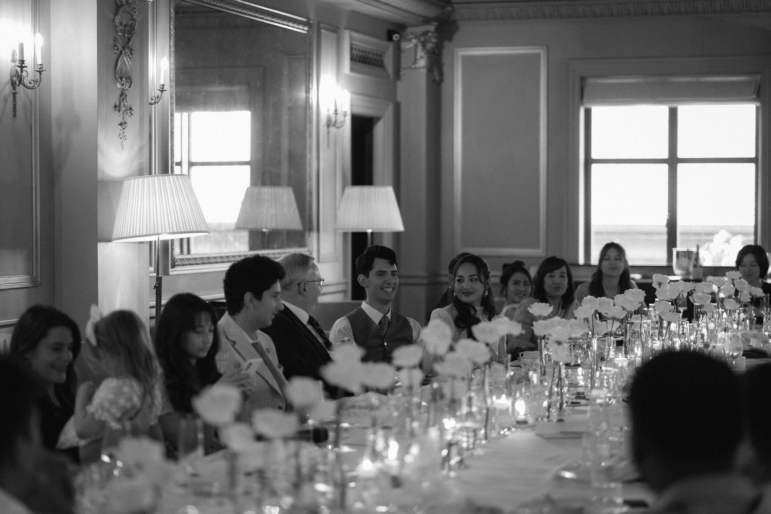 Elegant black and white photo of guests seated at a long banquet table during a formal dinner reception.