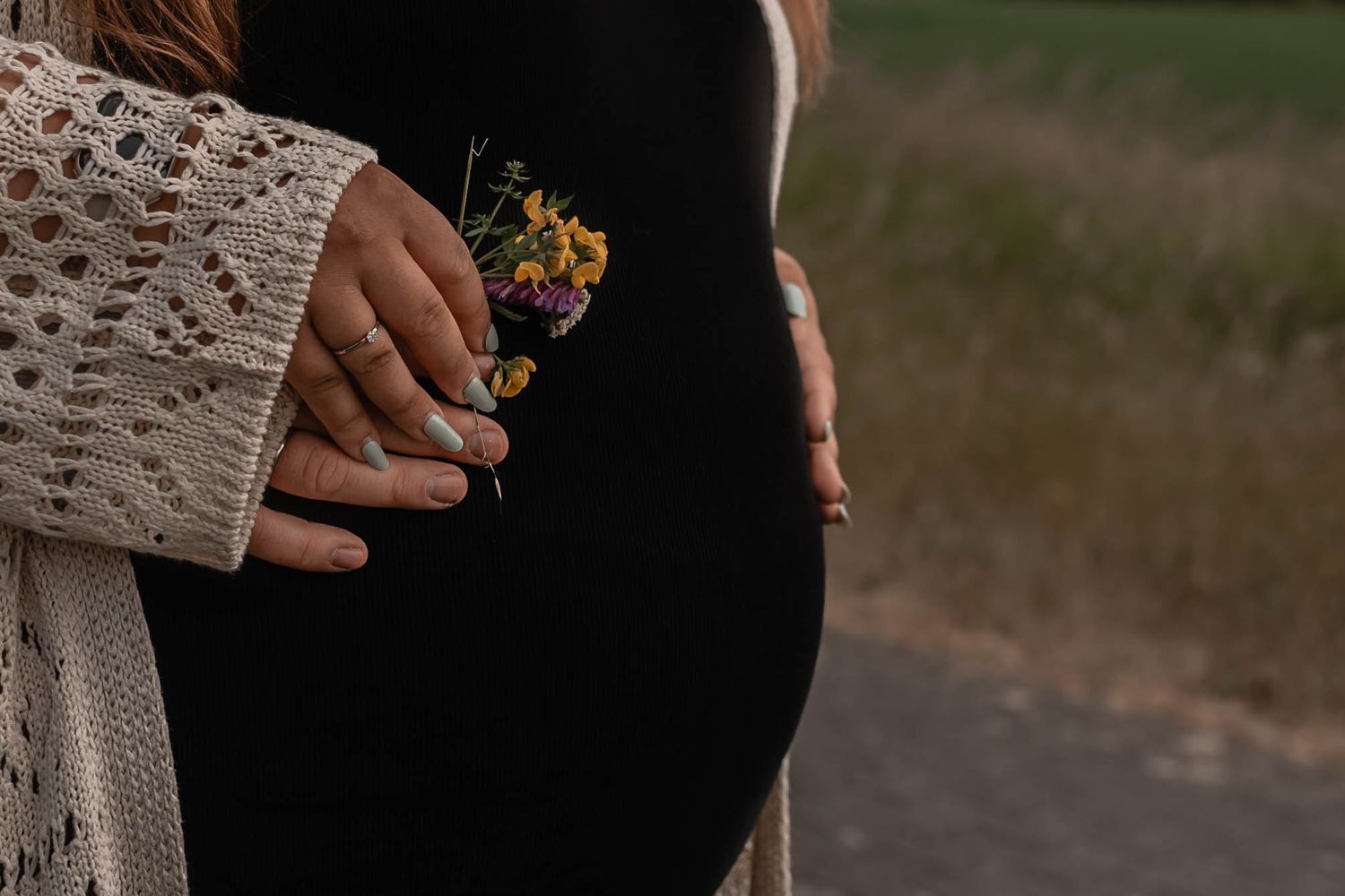 A close-up view of hands holding colorful bouquet flowers while taking wedding ceremony photos outdoors.