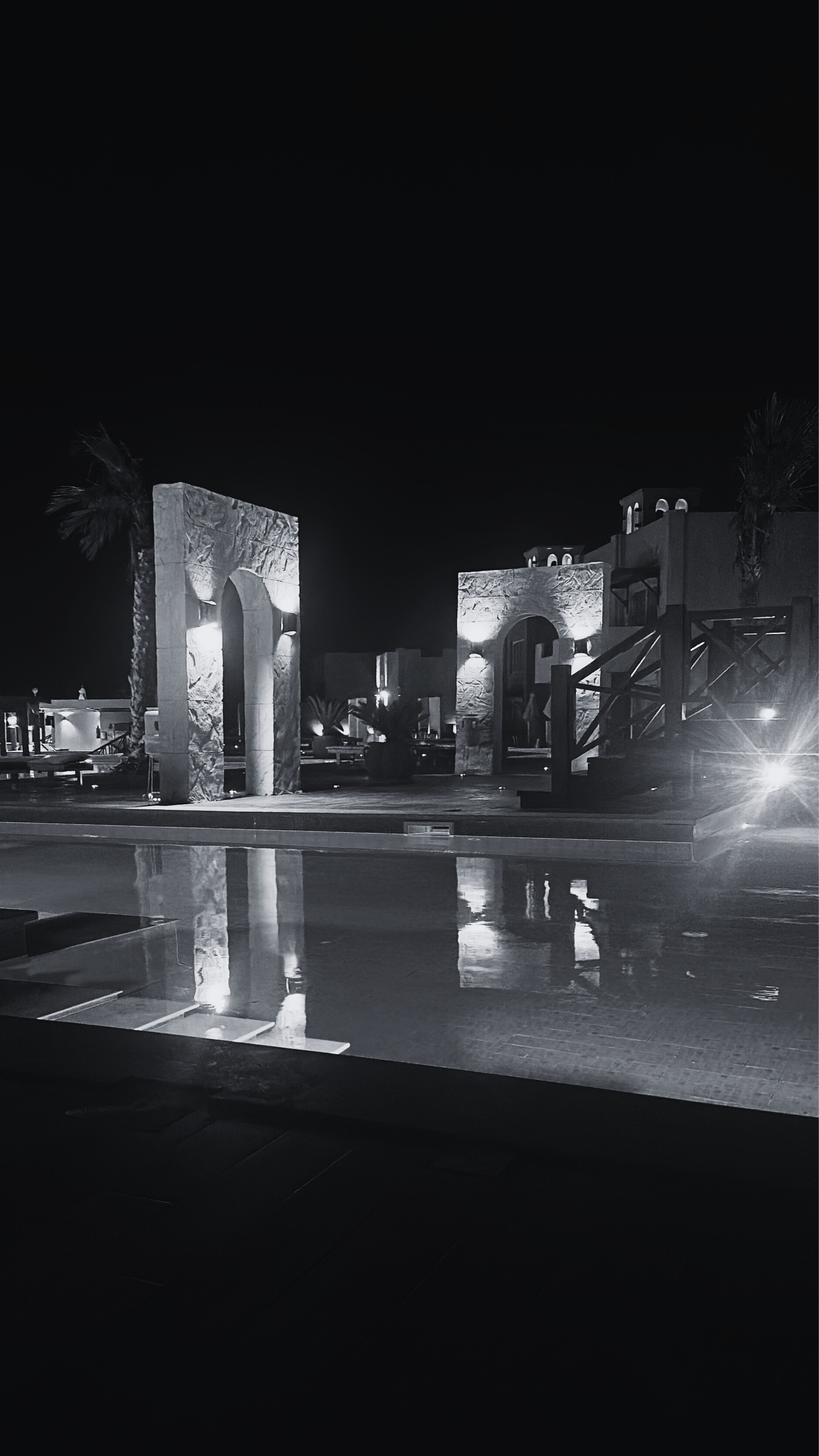 A series of illuminated concrete structures creating an artistic light installation at night in an urban setting.