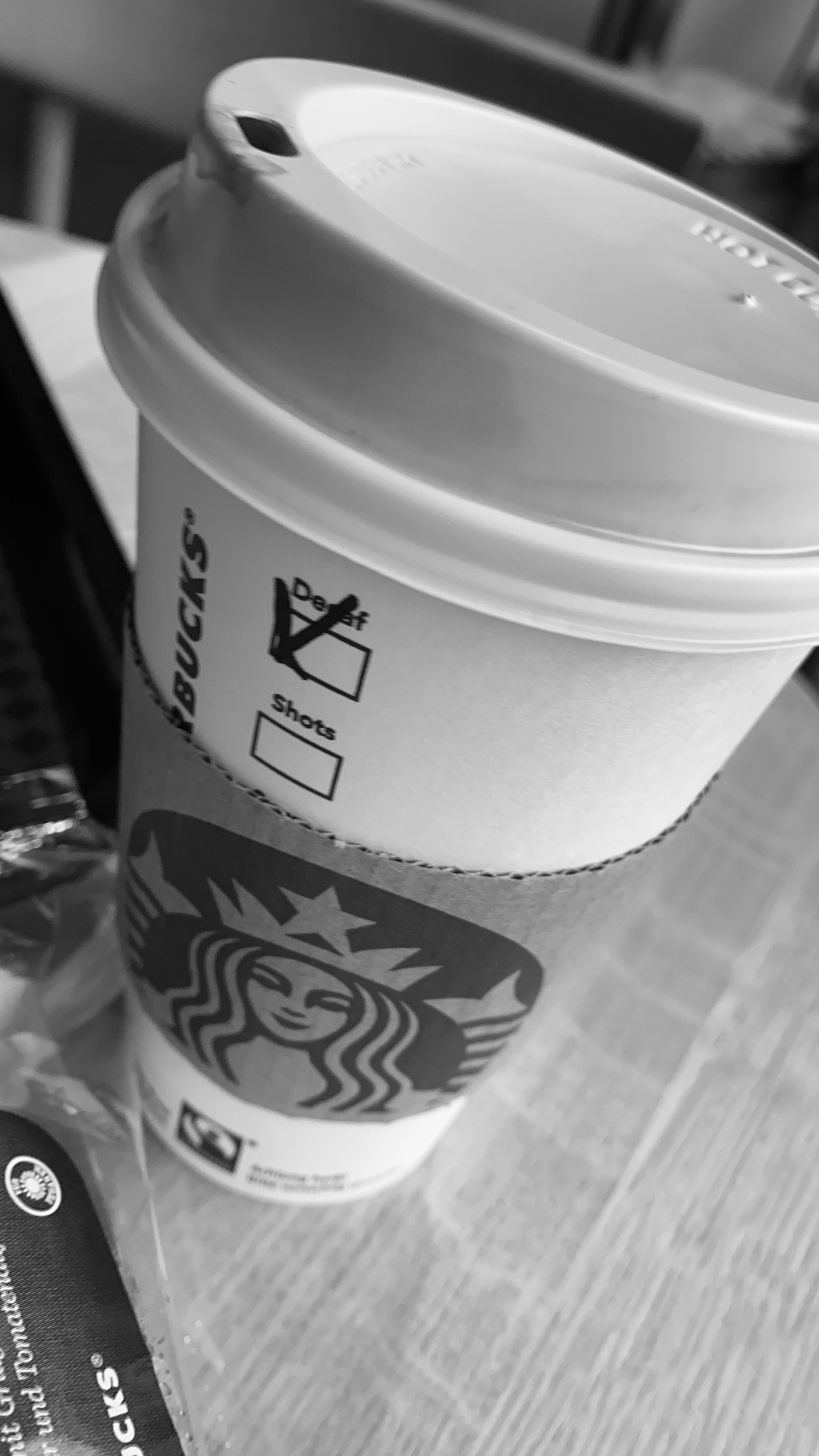 A close-up view of multiple Starbucks coffee cups with lids arranged in a row on a wooden surface.
