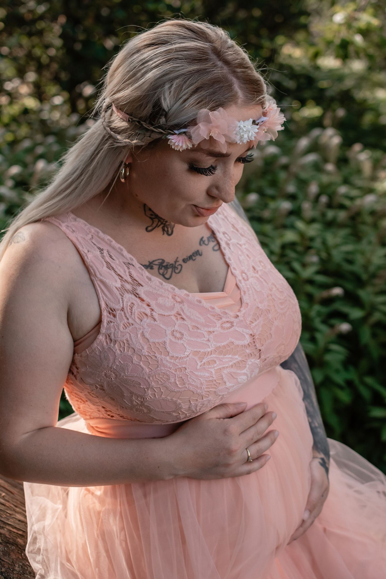 A pregnant woman in a pink lace maternity dress cradles her baby bump in four similar outdoor portraits.