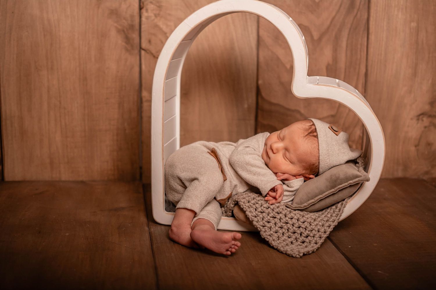 A composite of newborn photographs arranged in a sequence showing sleeping baby in various poses on brown backdrop.