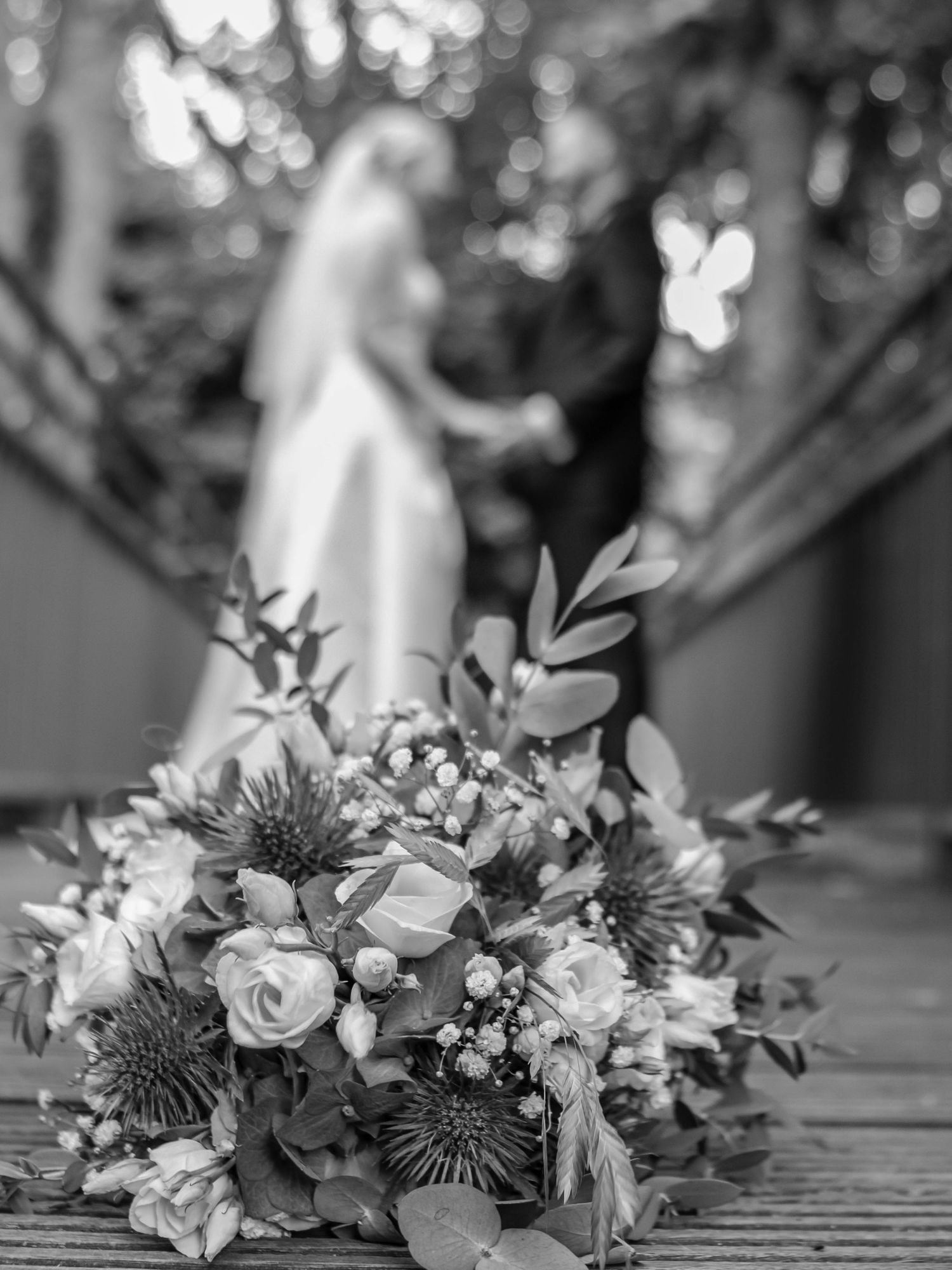 Black and white wedding floral centerpiece with roses and pincushion protea on an elegant dining table.